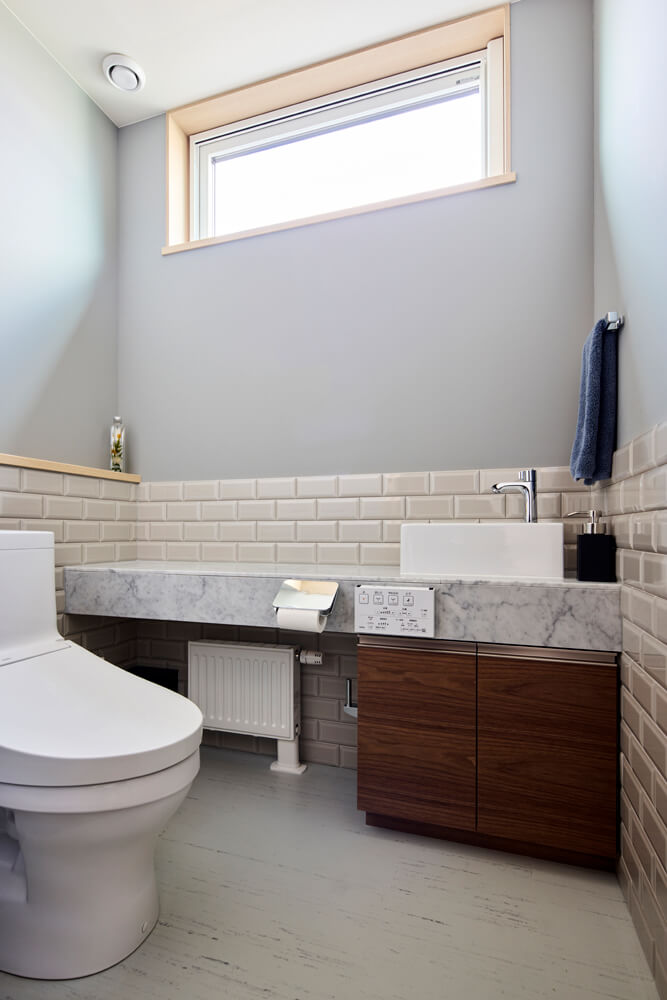 1階のトイレは石材のカウンターにベッセルタイプの洗面ボウル、サブウェイタイルで質感の良い空間に