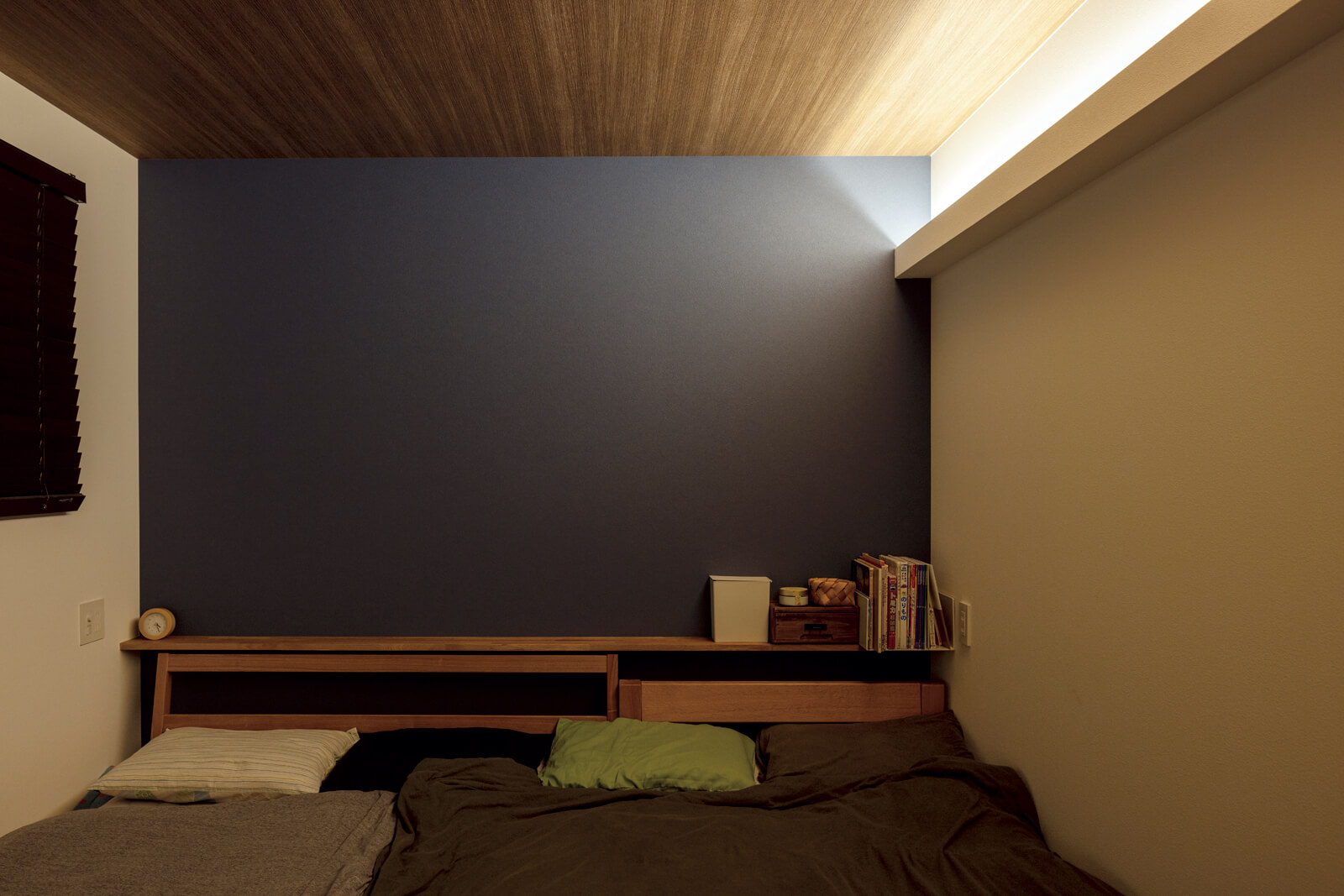1階にある寝室は落ち着いた雰囲気を重視し間接照明のみに。ネイビーのアクセントクロスは2階のフリースペースとおそろい