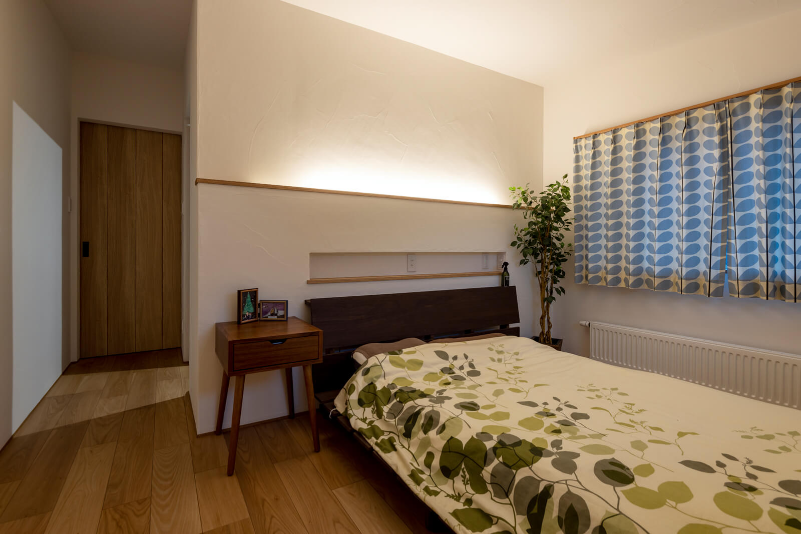 ベッドのヘッドボードにLED照明を組み込み、壁面を照らした寝室の間接照明