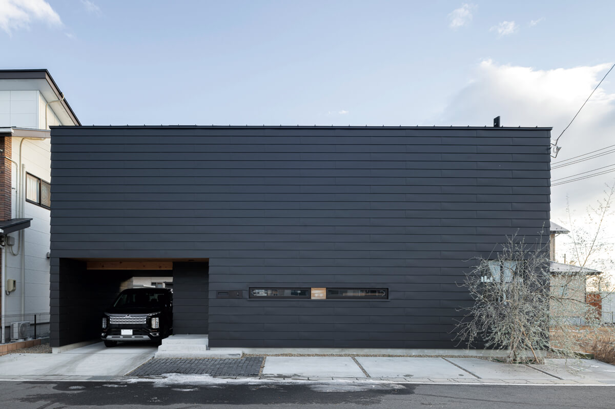 水平方向に張った黒いガルバリウム鋼板仕上げで、洗練された印象の外観。道路に面した北面には窓や開口部を極力なくしてプライバシーを確保