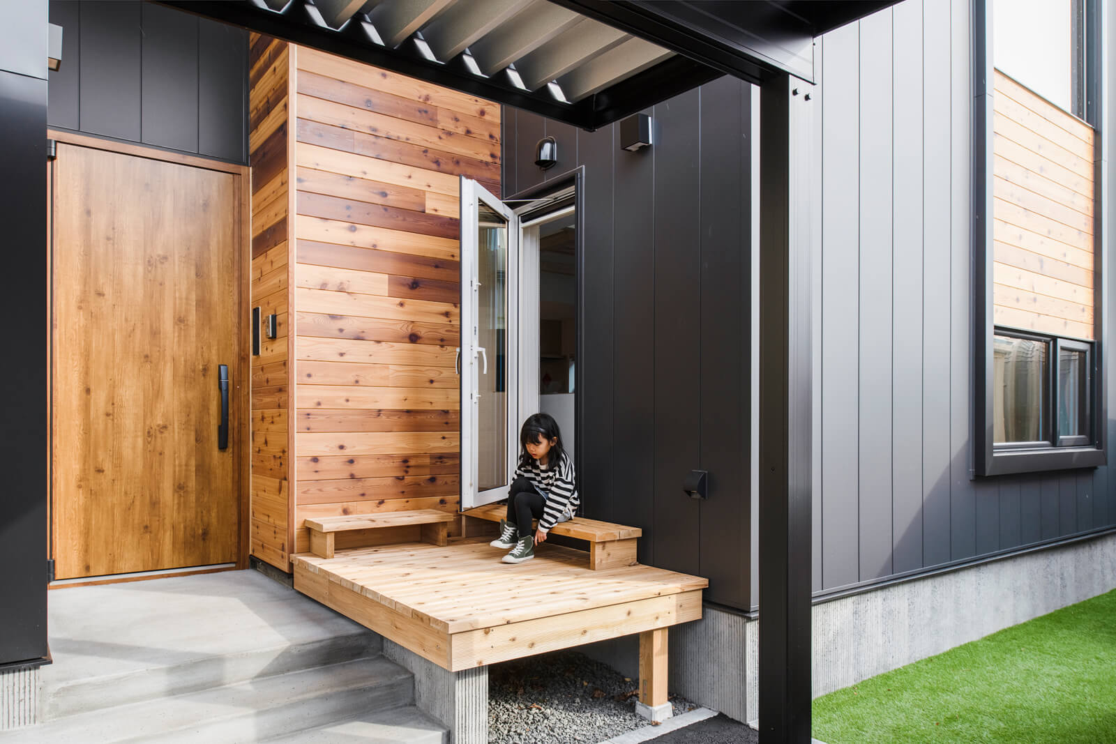 内と外をつなげるウッドデッキは玄関ポーチに配置。コンパクトなサイズながらも、子どもたちの遊び場やベンチ代わりになるなど機能的な空間となっている。レッドシダーの外壁と相まって、外観に木の温もりを添えてくれる