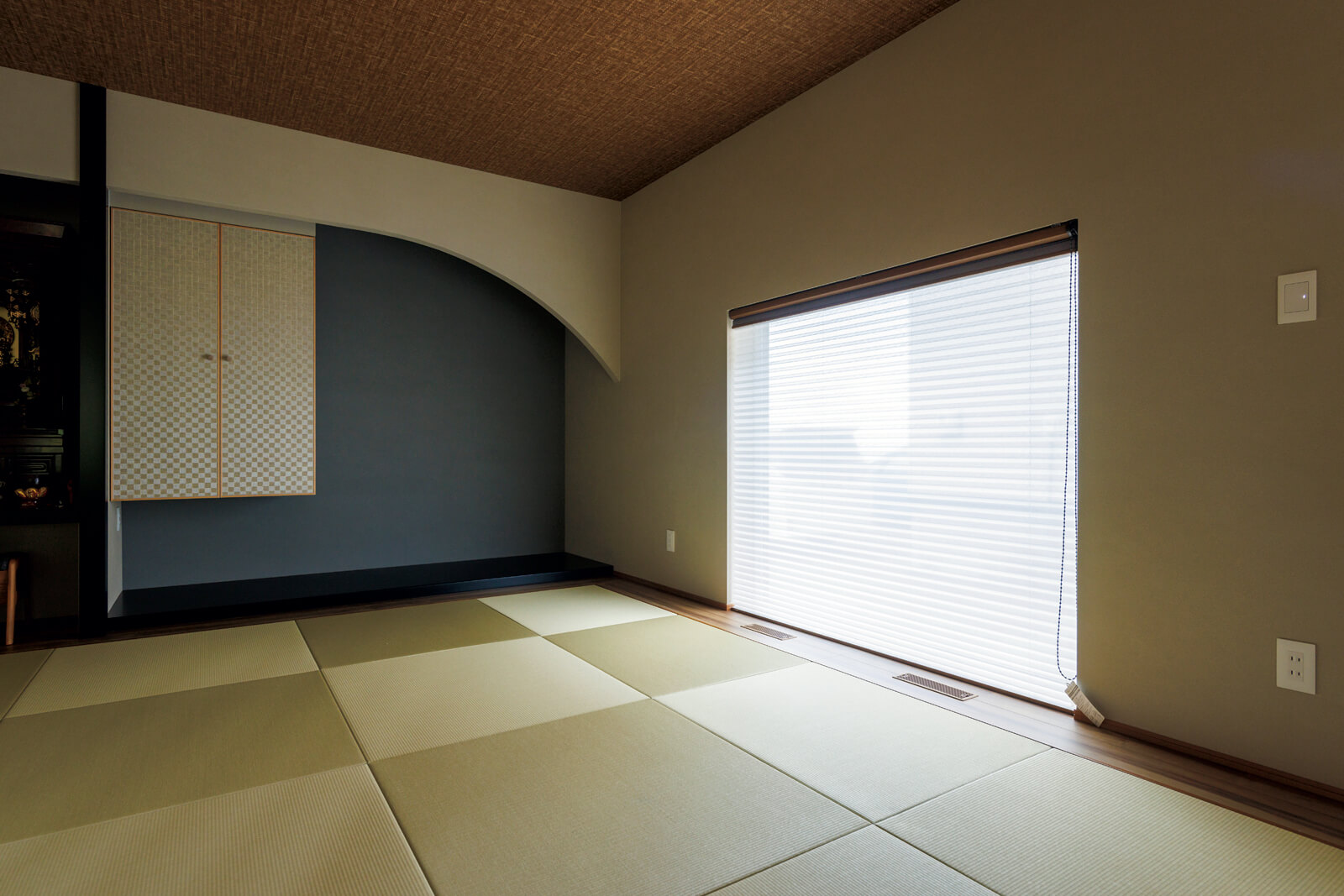 仏壇と床の間を備えた8畳の和室。モダンな床の間と琉球畳で、リビングからの続き間としても違和感なくなじむ