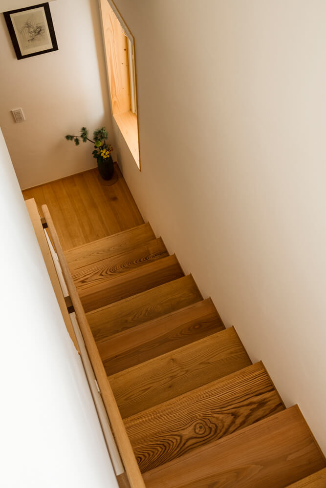 マカバやタモ、ナラを用いた階段は、蹴上が低く上り下りしやすい。タモ無垢材を用いた造作の手すりは、握りやすいように内側に手刻みの細工が施されている