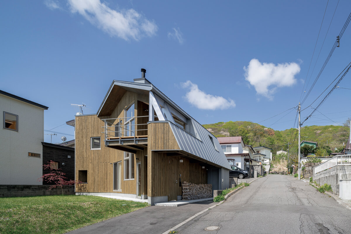 立地条件から導き出したのは、寄棟屋根の建物を上から斜めにカットしたような形の家。庭と海へ向けて開いた大きな窓が、内と外を融和的につなぐ