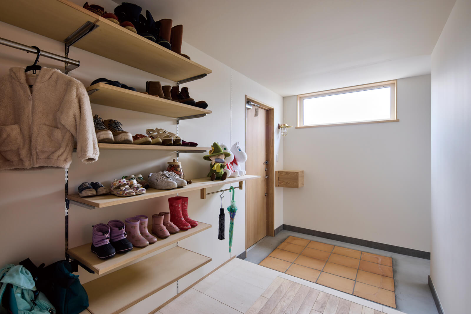 アウターや靴、傘など、出かける際の身支度をすべて整えられる広い玄関ホール。オープンな造作収納側の床は石を敷いて、汚れを拭き取りやすいように配慮している