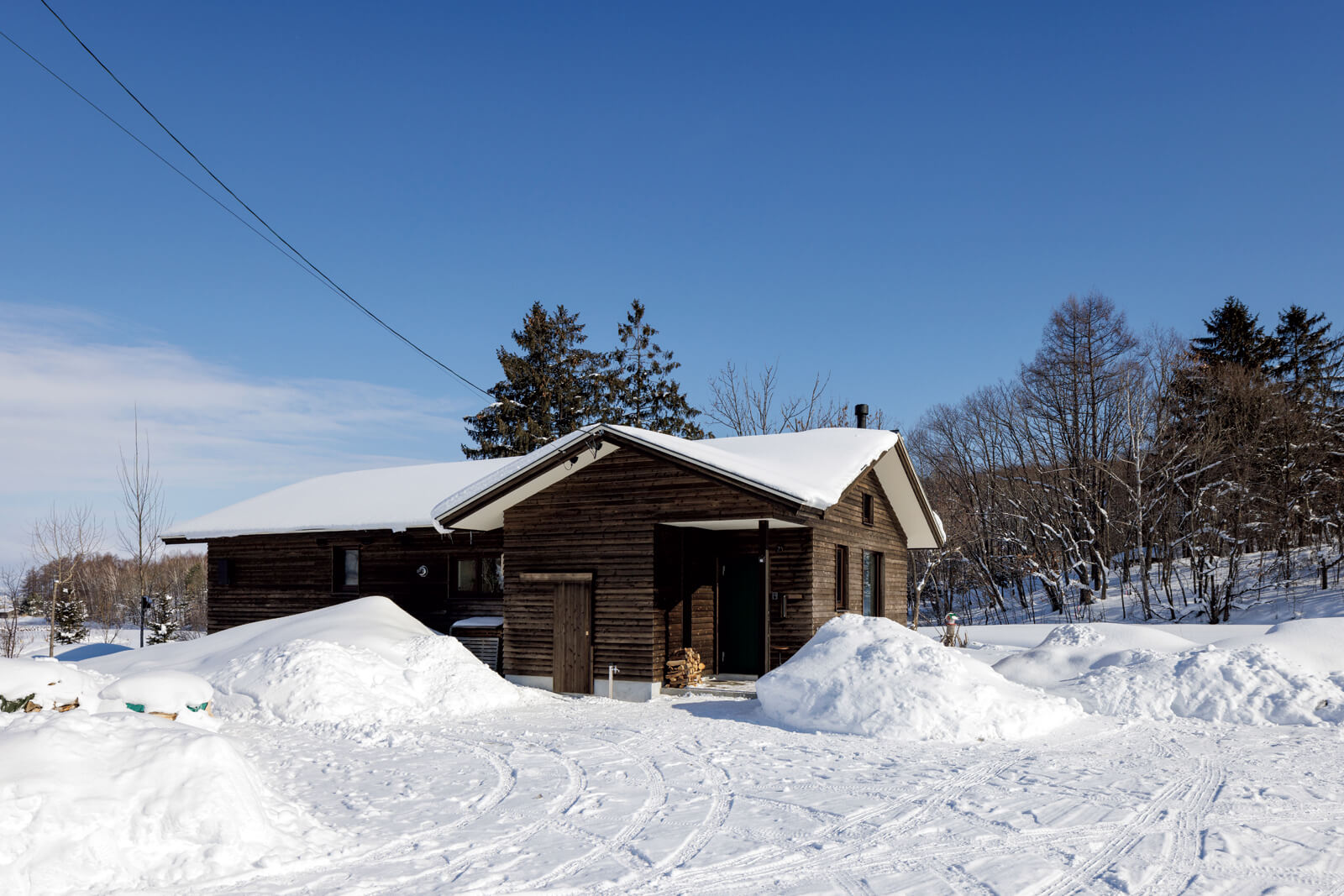 道南スギで仕上げた外観は周囲の自然にマッチ。広い敷地を生かし、あえて落雪屋根にしてコストも抑えた