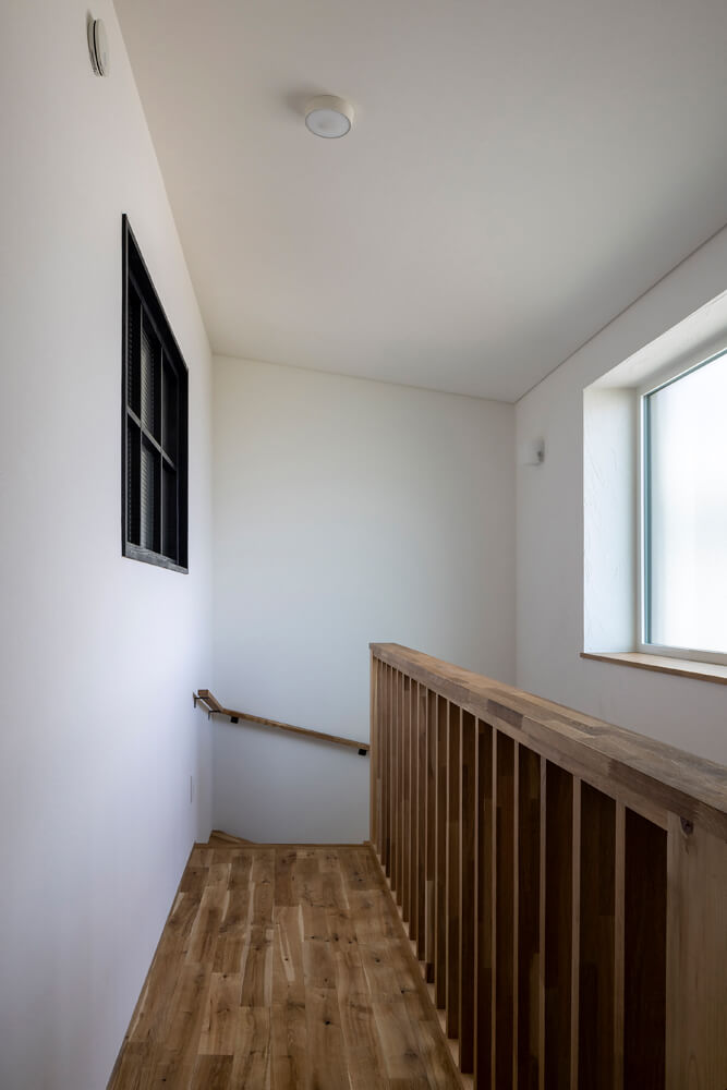 大きな窓を設え明るい階段に。手すりは木製でやわらかい雰囲気