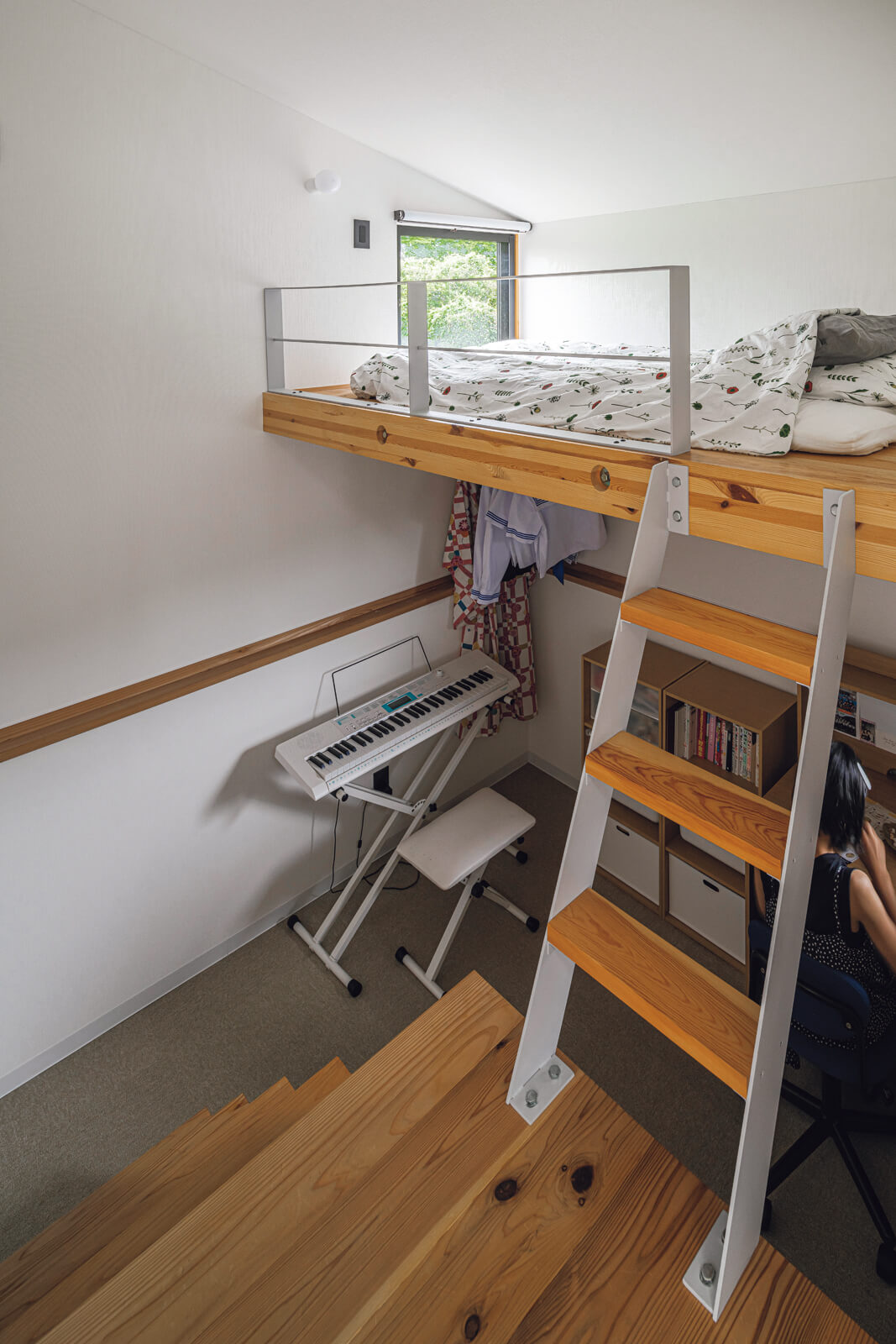 ダイニングの両サイドに、高い基礎を生かした4.5帖の子ども部屋を設けた。はしごを上ると造作のベッド、ステップを下りると勉強机と収納があり、上下の窓が閉塞感を解消している