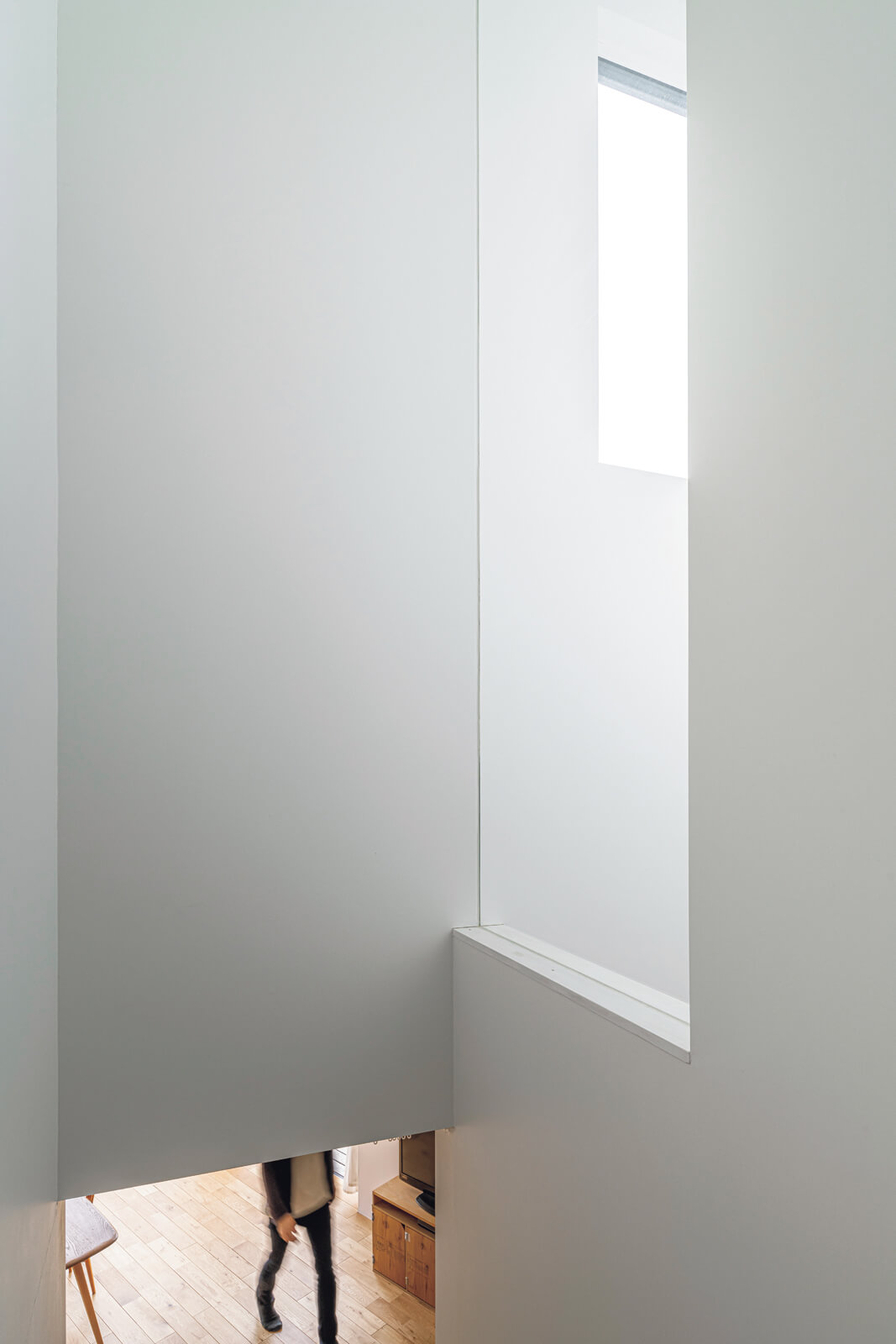 玄関の上部の大きな窓から射し込む外光が、ガラスの間仕切り壁を介して、窓がない廊下や階段まわりを明るく照らす