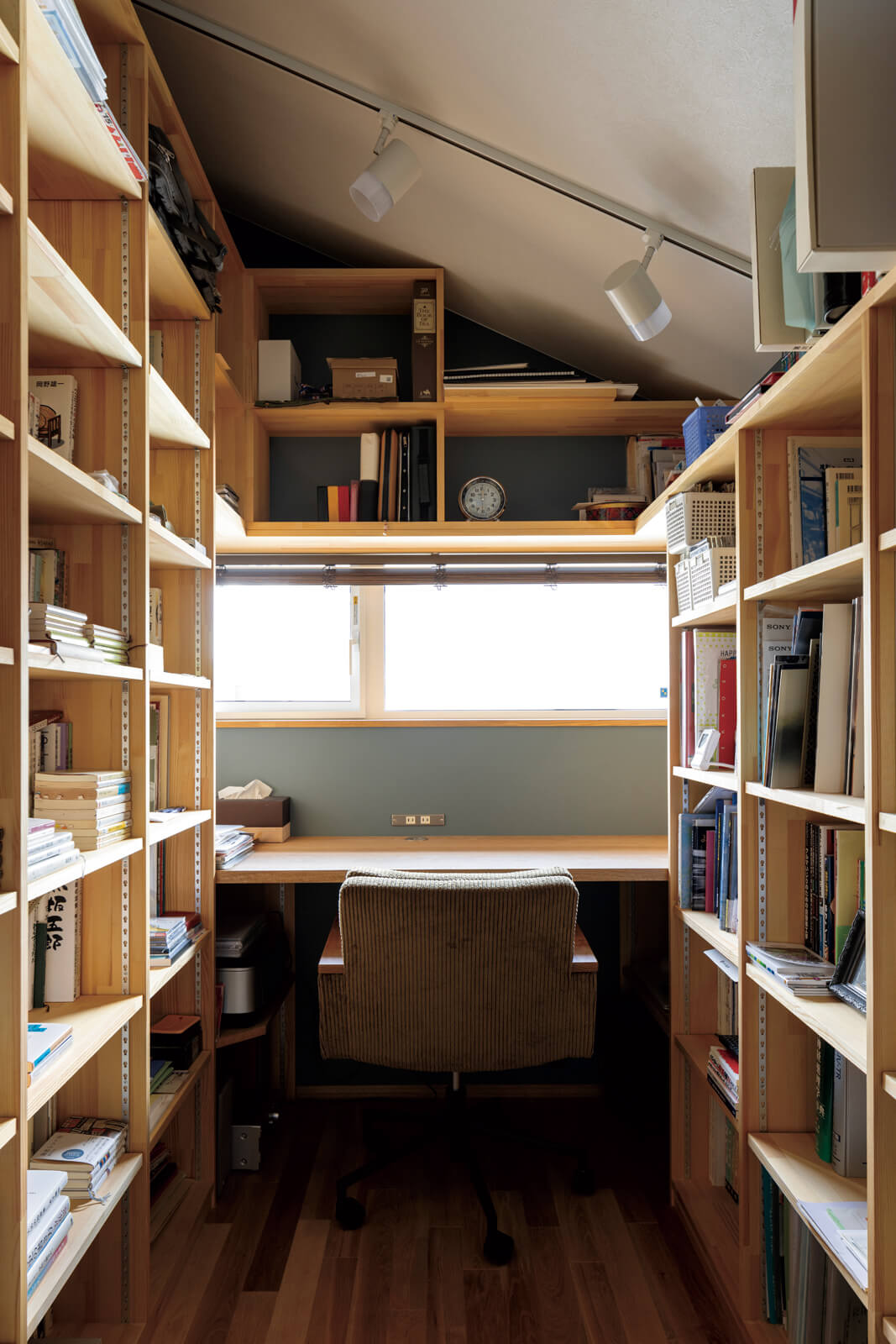 天井まで届く造作本棚が印象的なIさんの書斎。階段側の小窓でリビングの様子が感じられる