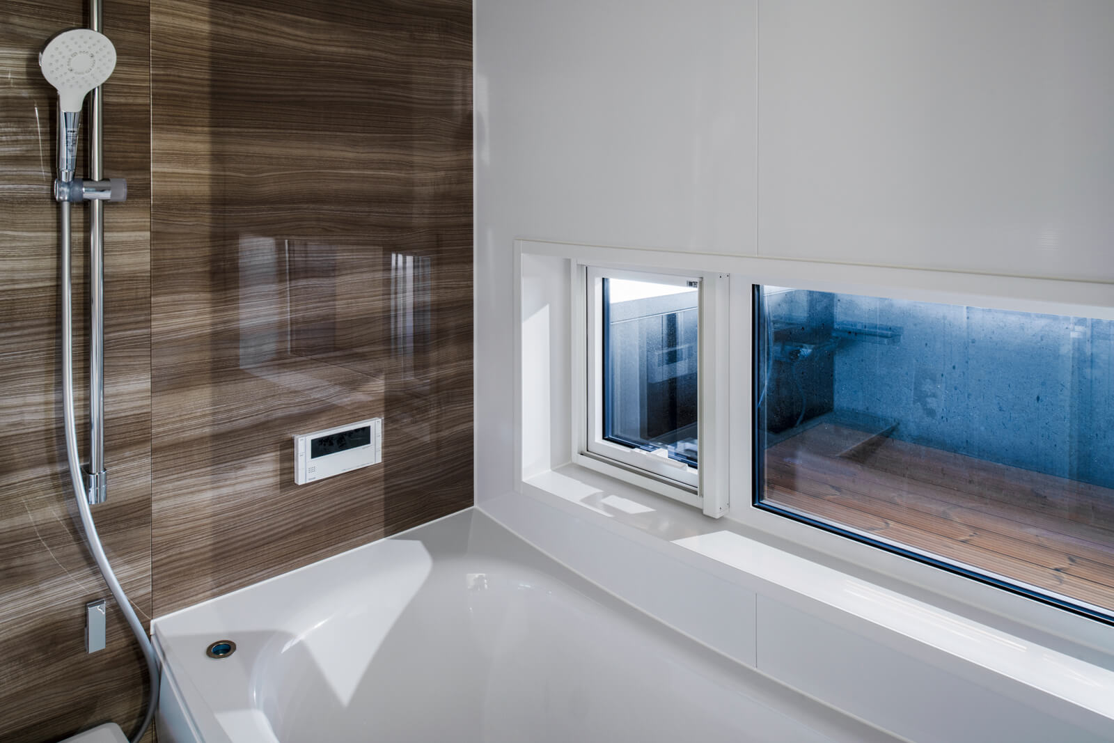 浴室には低い位置に窓を設けて、坪庭を眺められるよう設計。露天風呂気分が味わえる