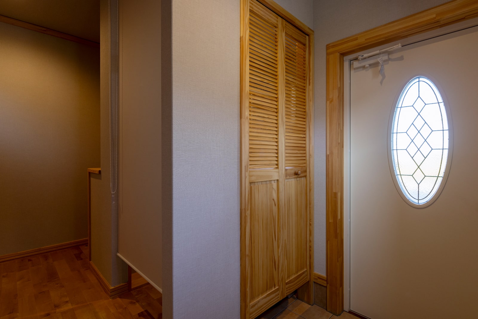 スウェーデン製の断熱ドアを採用した玄関。左のルーバー扉の奥は、玄関ホールにも出入り口を設けたシューズクローゼット