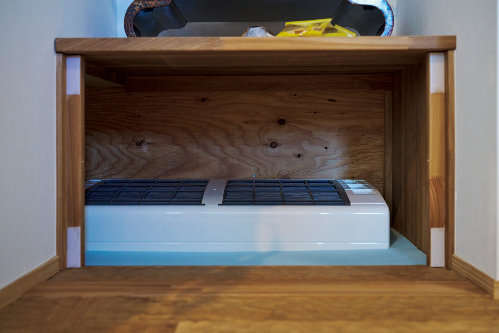 床下暖房のエアコンは、和室の物置の下に設置し、木製パネルで目隠しできるようになっている。この12畳用エアコン1台で家中を暖められる