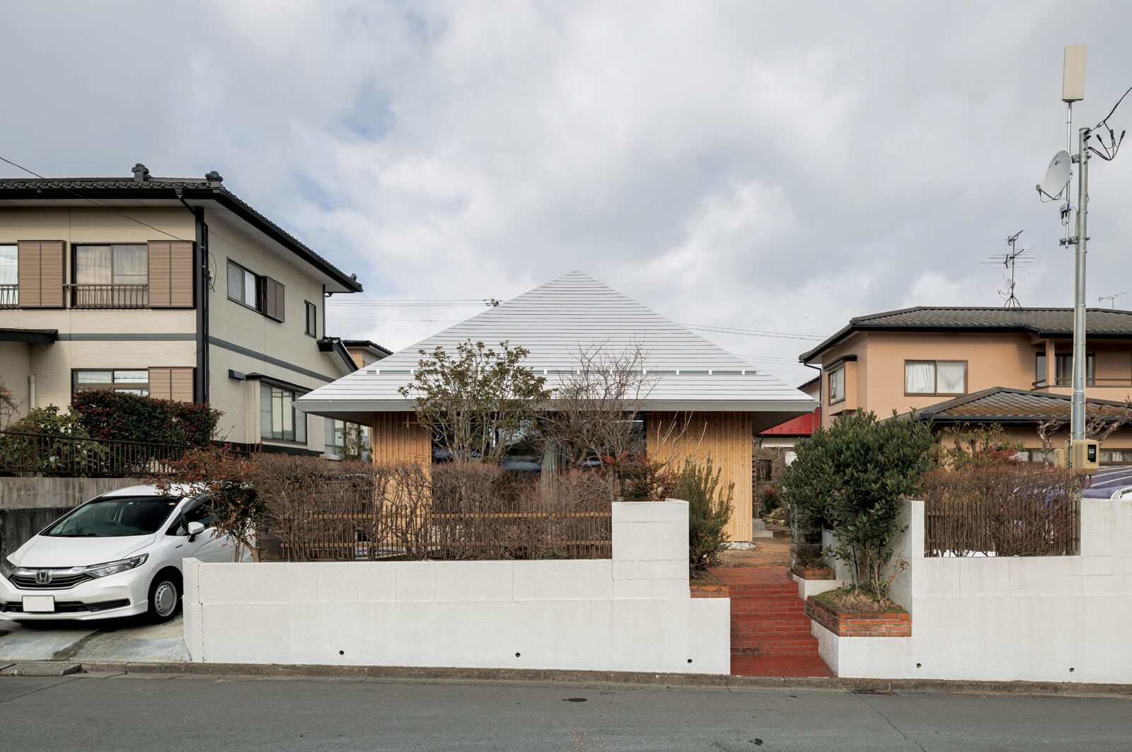 敷地の中央に配した寄棟屋根のAさん宅。外壁は、自然塗装を施した屋久島地杉で仕上げた。建物の四方はぐるりと庭になっており、四季折々の庭木や花を家の中からも楽しめる