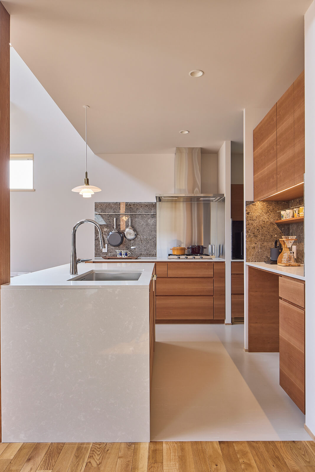 キッチンは側面とトップに、洗面台と同じクォーツスラブを採用し、収納部はチェリー材を使った。石と木の調和が美しいキッチンに、PHランプがアクセントになっている