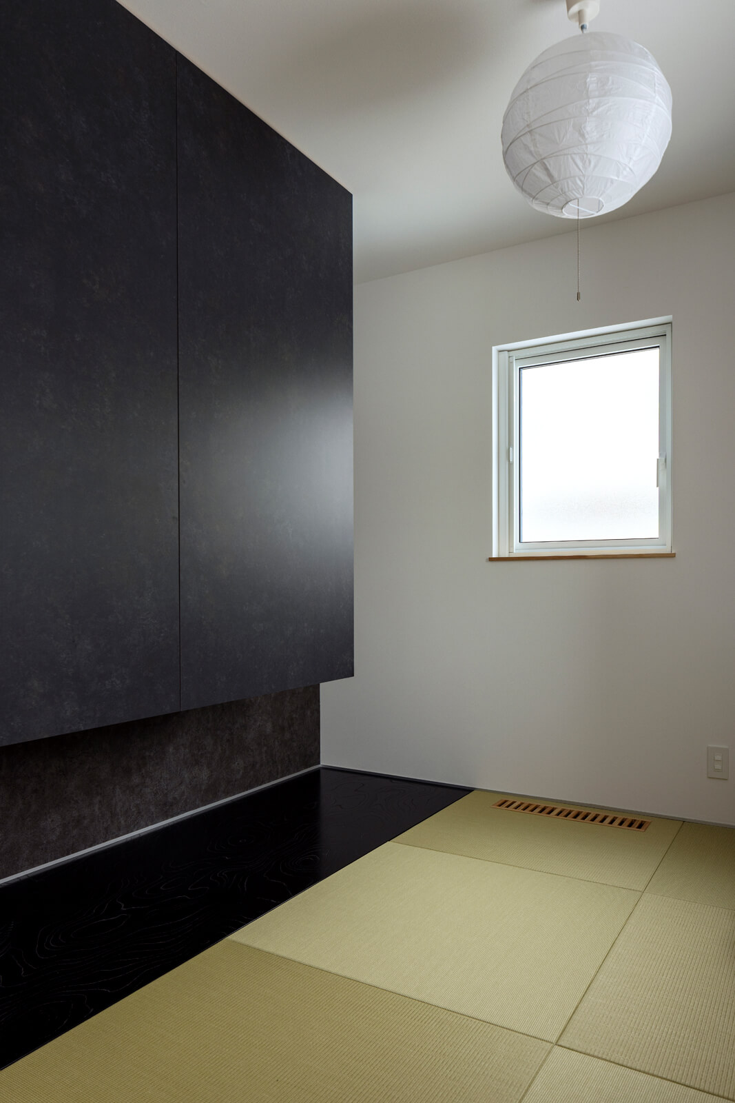 リビング続きに設けた和室は予備室を兼ねる。黒い床板は、浮造りを施したケヤキ材。琉球畳や浮き押し入れの建具にグレーのクロスを用い、和モダンな雰囲気に仕上げた
