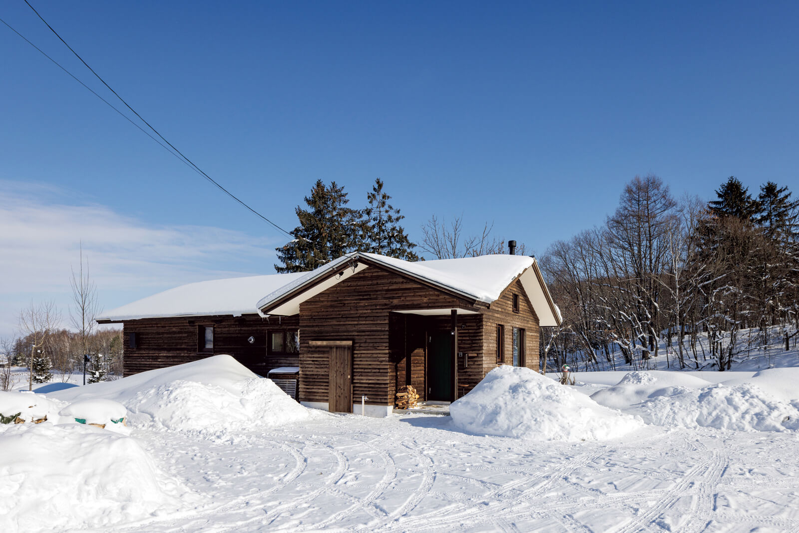 道南スギで仕上げた外観は周囲の自然にマッチ。広い敷地を生かし、あえて落雪屋根にしてコストも抑えた