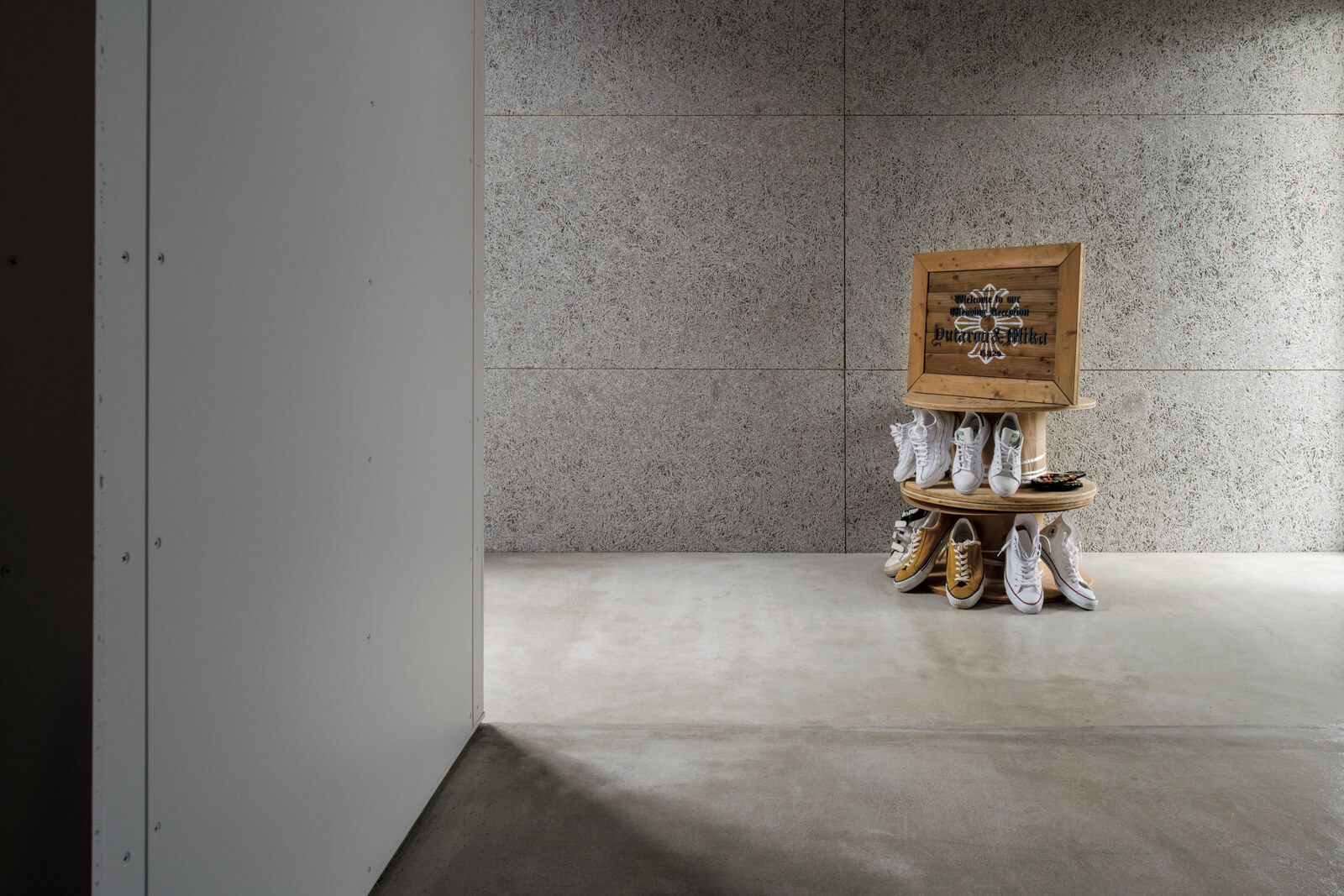 モルタルと木毛板からなるシンプルなエントランス。コレクションのスニーカーが出迎えてくれる
