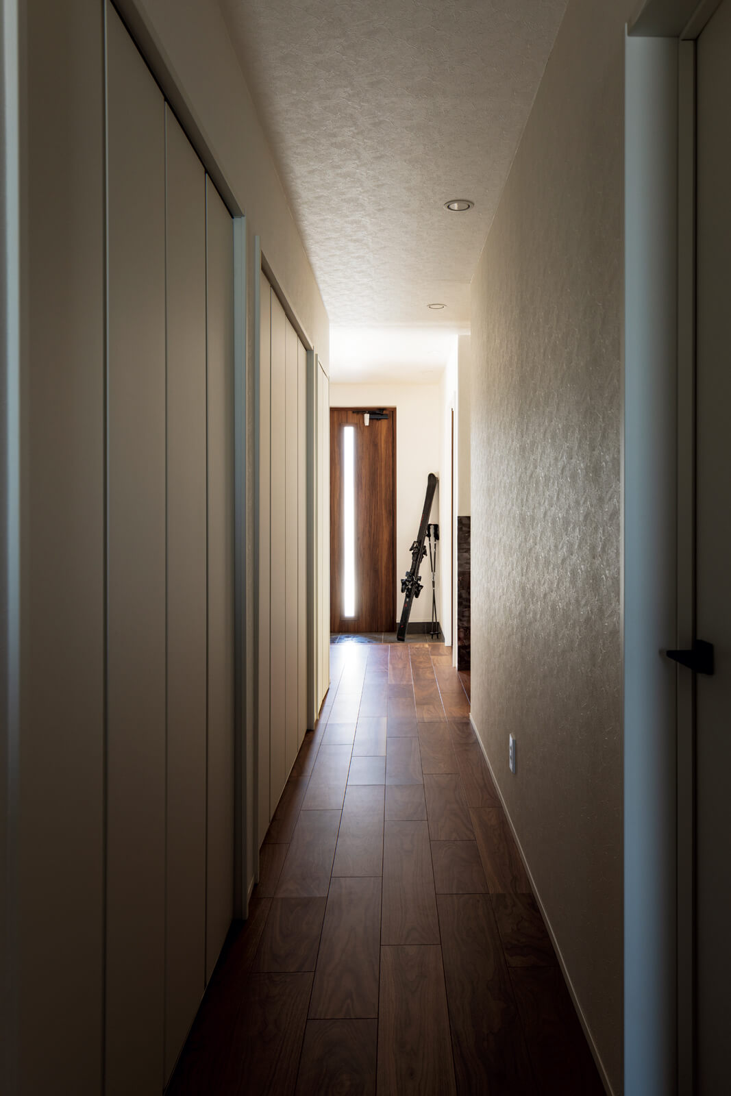 玄関ホールから延びる廊下の右手には家族の個室、左手にはLDKや水まわりを配置。大容量の壁面収納を備えた廊下は、家族の暮らしのオン・オフのスイッチの役割を果たす