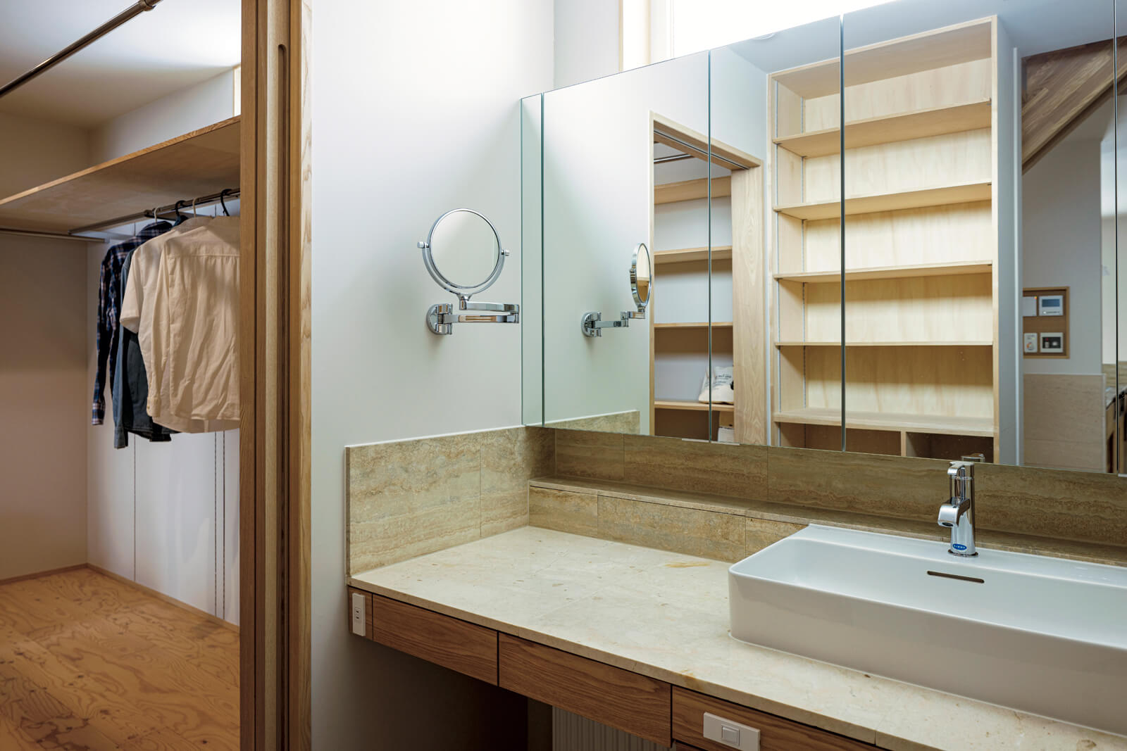 ファミリークローゼットに隣接する洗面スペース。すっきりとしたデザインの洗面台、背面収納棚は造作仕上げ