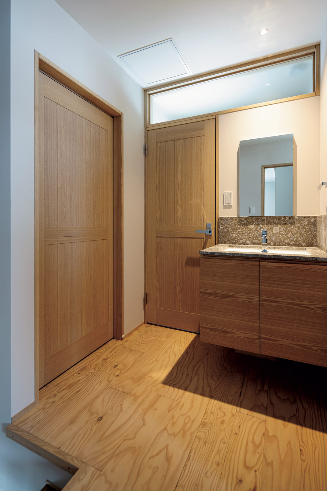 2階の階段ホールに独立型手洗い、トイレを設置。左手の扉の奥は、季節用品などをたっぷりしまえる納戸。2階の床はすべて、丁寧に磨いた構造用合板を採用している