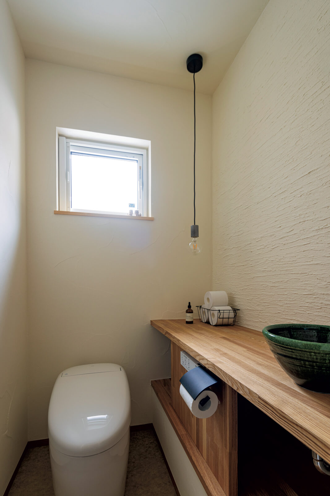 タモ材を用いた造作カウンター、趣ある陶器の手洗いボウルを用いたトイレ
