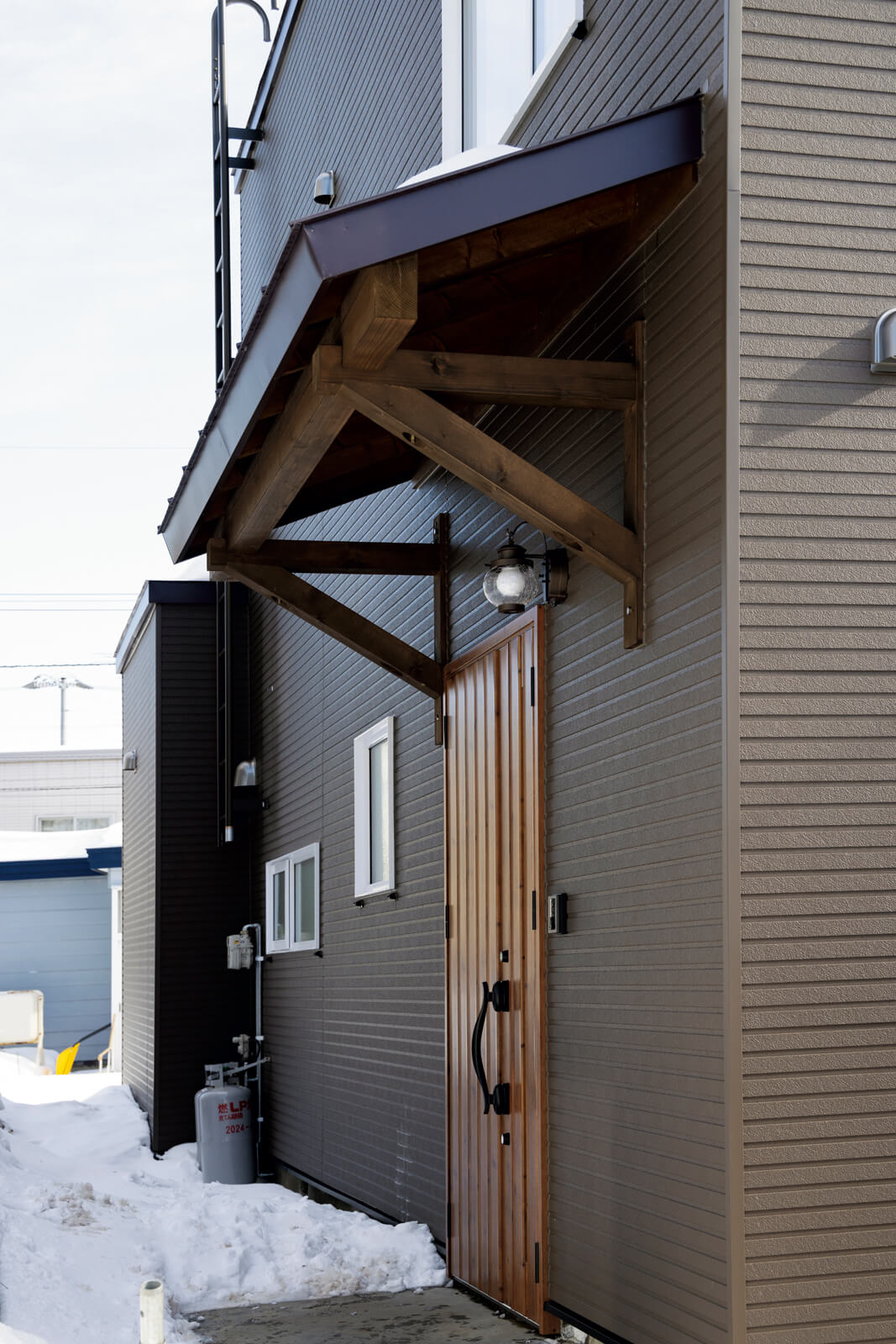 既存の風除室を取り除き、新たに雪や雨を防ぐ小屋根をかけた玄関ポーチ。玄関ドアも断熱・気密性能の高いものに交換した