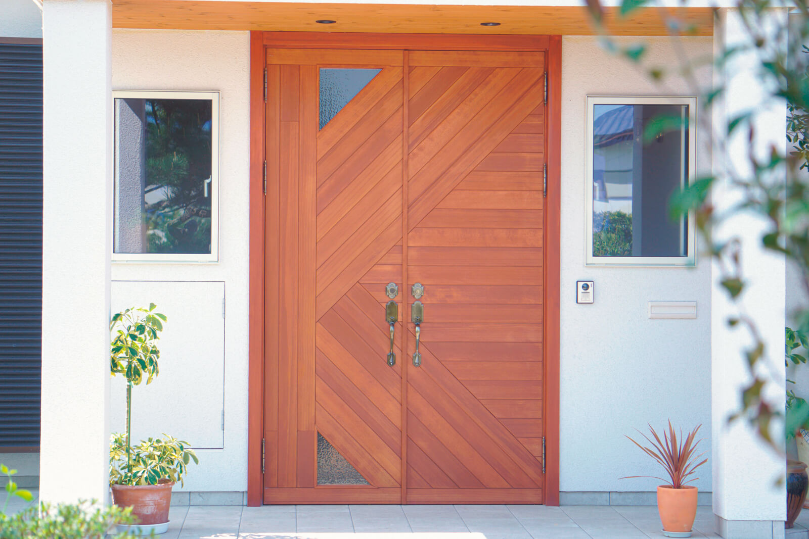 木製の玄関ドアは、名字のイニシャルをモチーフにデザイン