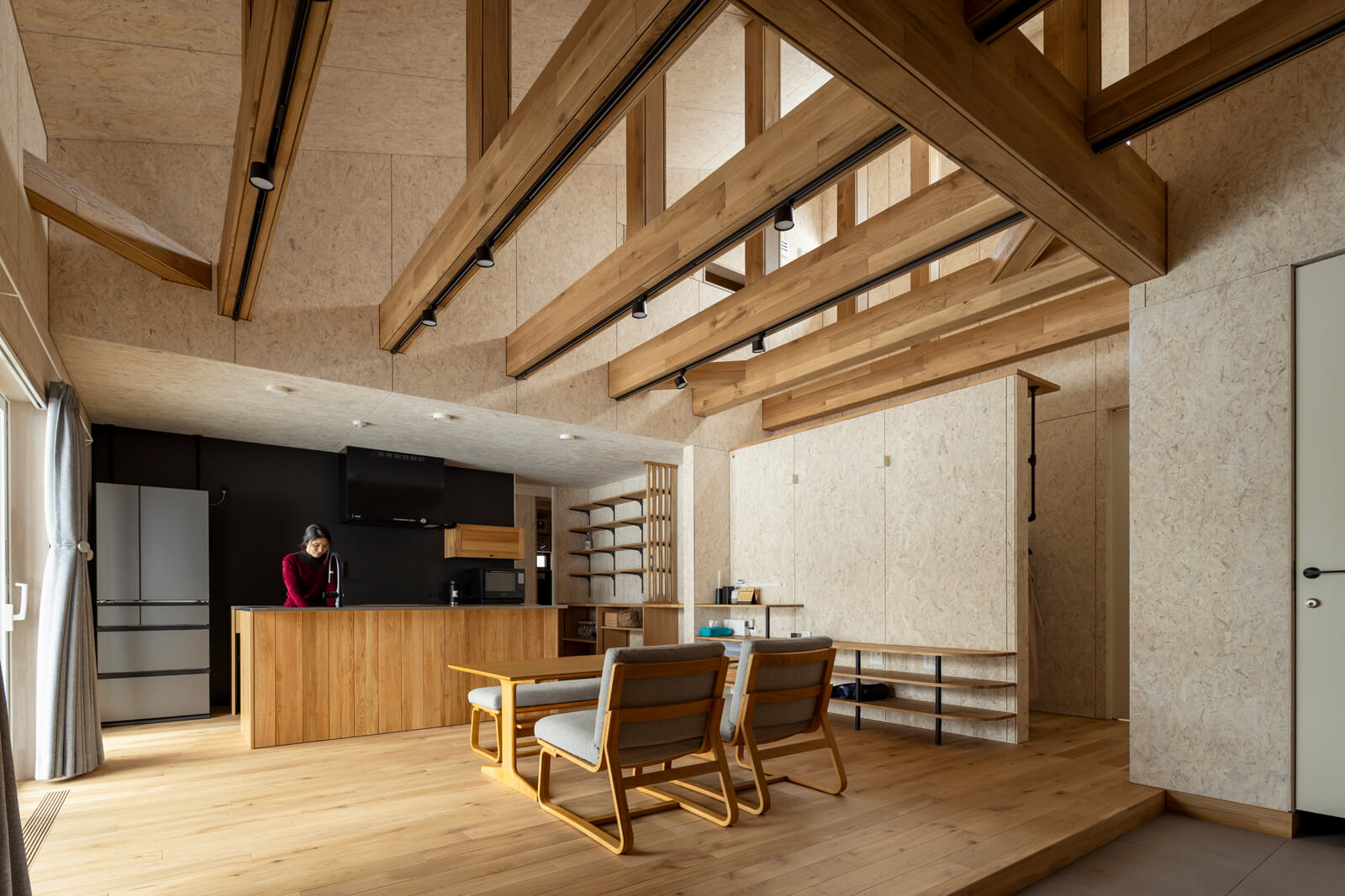 構造をダイナミックに現しにした開放感あふれるLDK。勾配天井の吹き抜けは最も高いところで6mあり、上部には採光のためにハイサイドライトを設けた