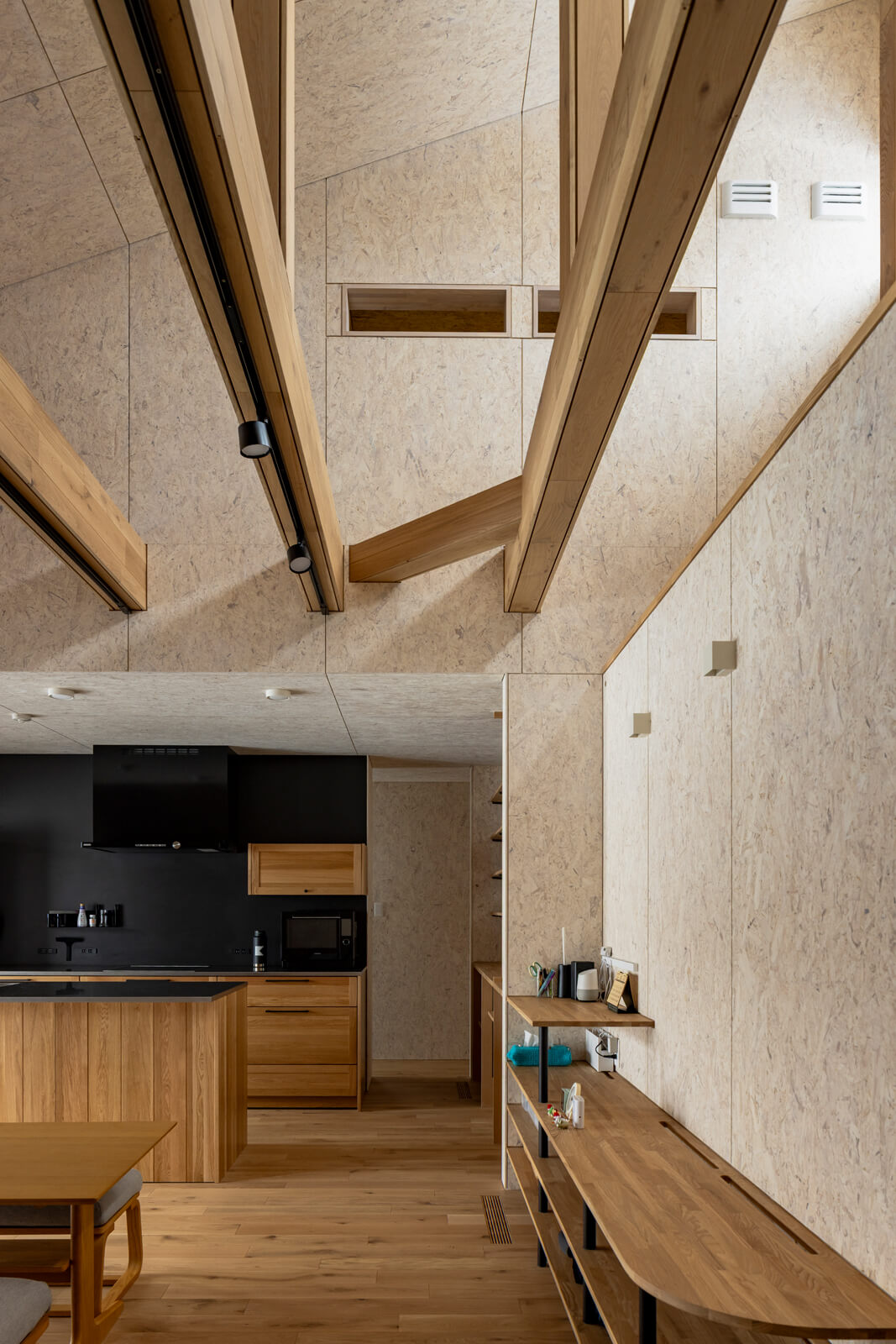 室内を巡った空気は、吹き抜けの壁面にある排気口(写真右上)から排出。吹き抜け上部に見える横長の開口の奥は、小屋裏空間を利用したロフト収納