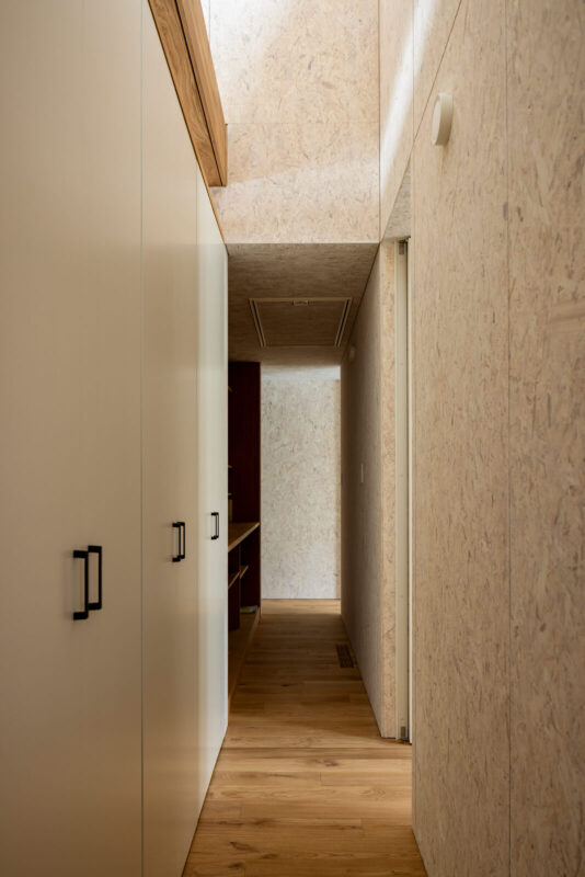 裏動線を玄関土間側から水まわり方向に見る。通路に沿って大容量の収納を設け、平屋にありがちな収納不足の悩みを解消