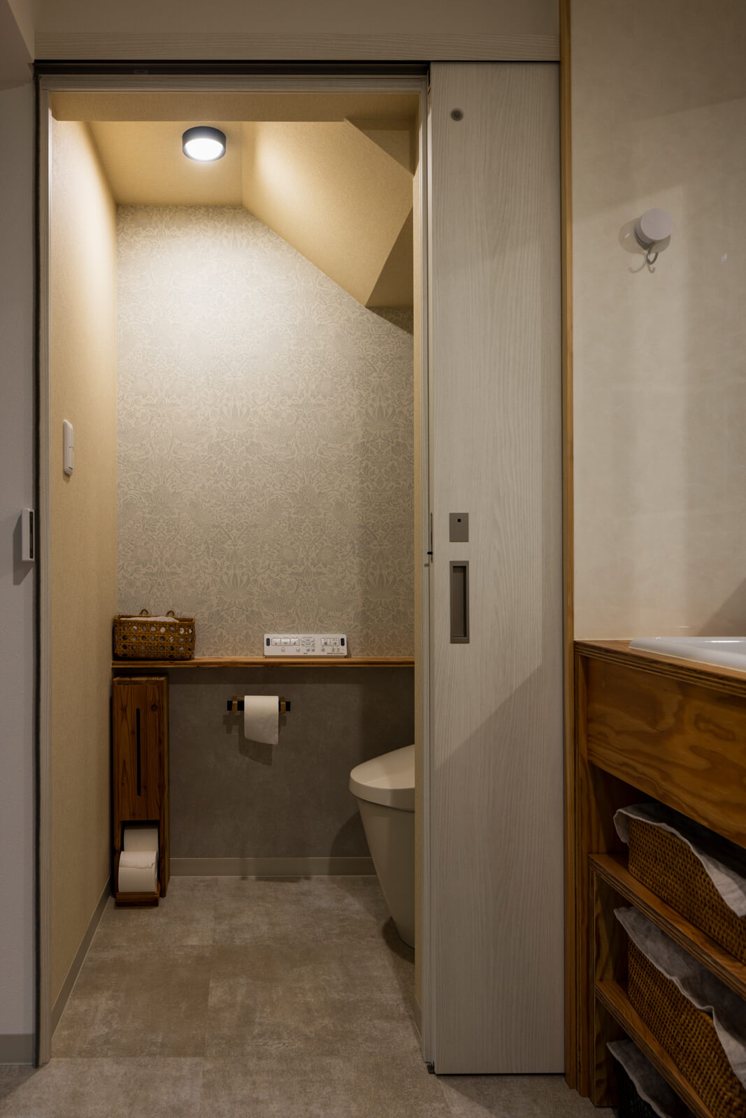 ユーティリティに隣接するトイレは階段下スペースを活用。腰壁カウンターを造作し、引き戸を採用した