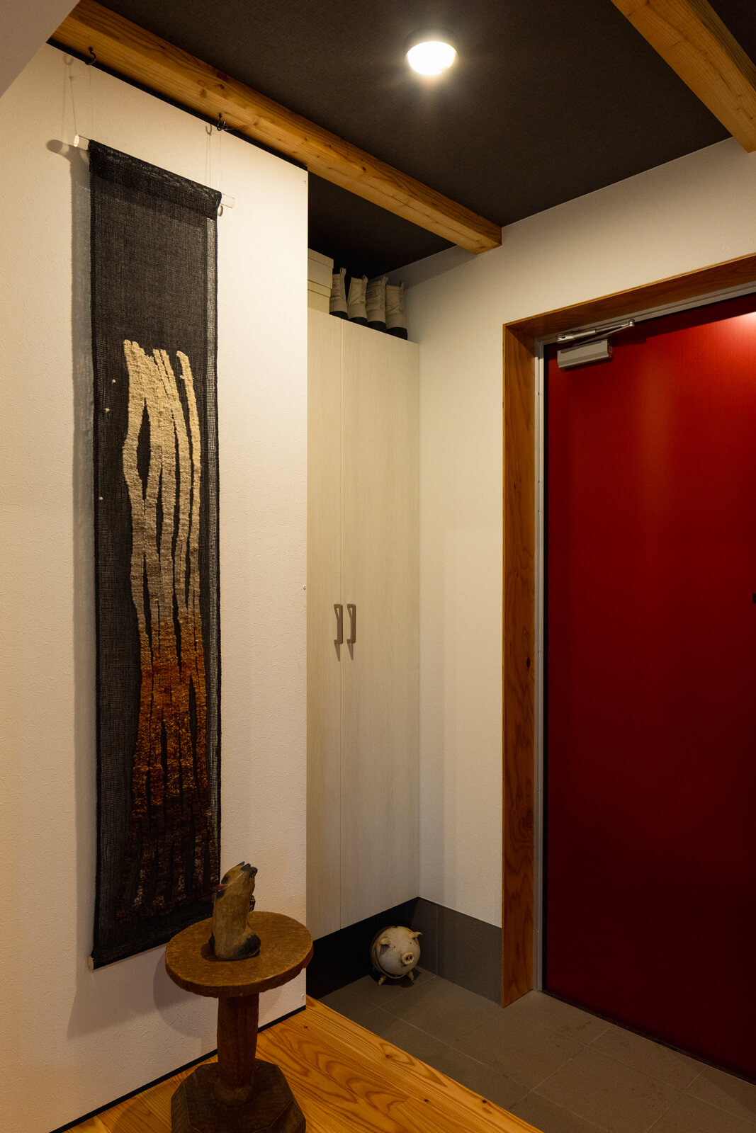 シューズボックスを造作したコンパクトな玄関には、奥さんが手織りを習った染織家の作品が飾られている