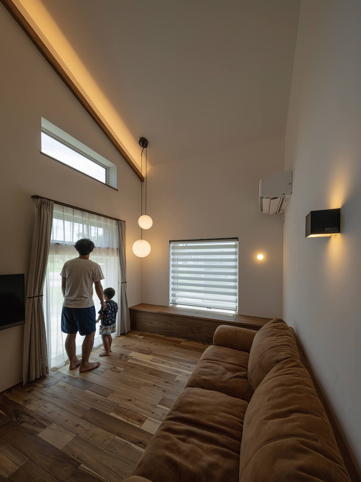勾配の高天井と2面採光を採用したリビングは開放感たっぷり。採光窓や壁付け照明、間接照明を用いて、光の美しさにもこだわった