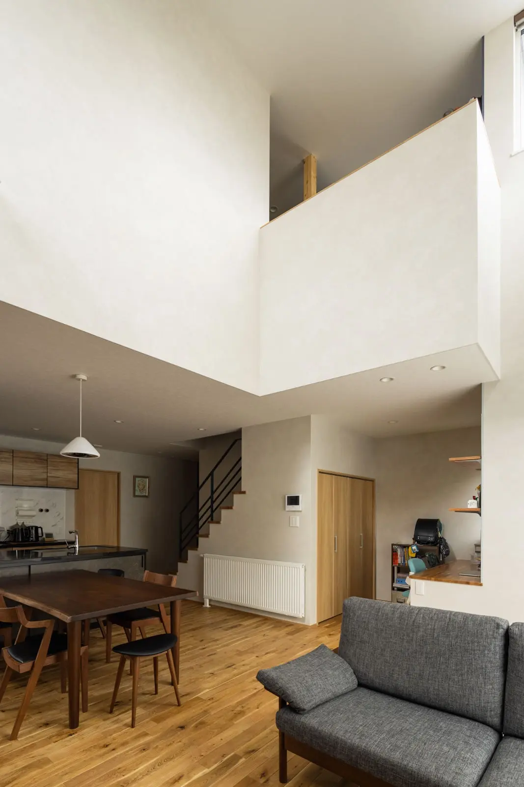 明るく開放的なリビング。ブラック、グレー系統のキッチンとの色彩を統一するため、ダイニングテーブルやチェア、ソファはセミオーダーでつくってもらった。2階の書斎スペースをあえて仕切らないことで、より広がりを感じる