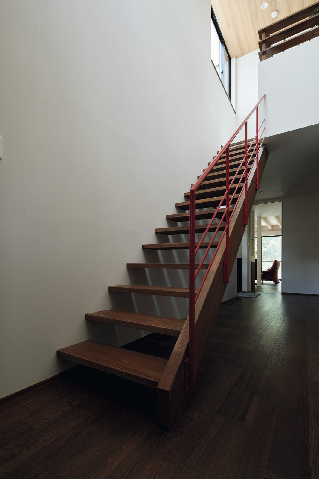 赤い手すりがアクセントの階段まわりは大きな吹き抜けに。階段を上った先には、外孫が遊びに来たときのための部屋や広いテラス、納戸などがある