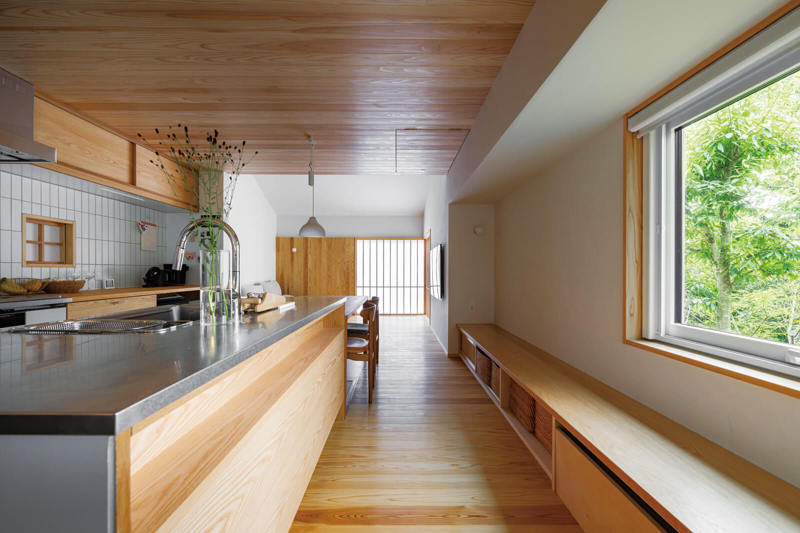 西側の窓に沿って設けた収納兼ベンチが便利。ベンチ下収納の端に床下エアコンを設置している