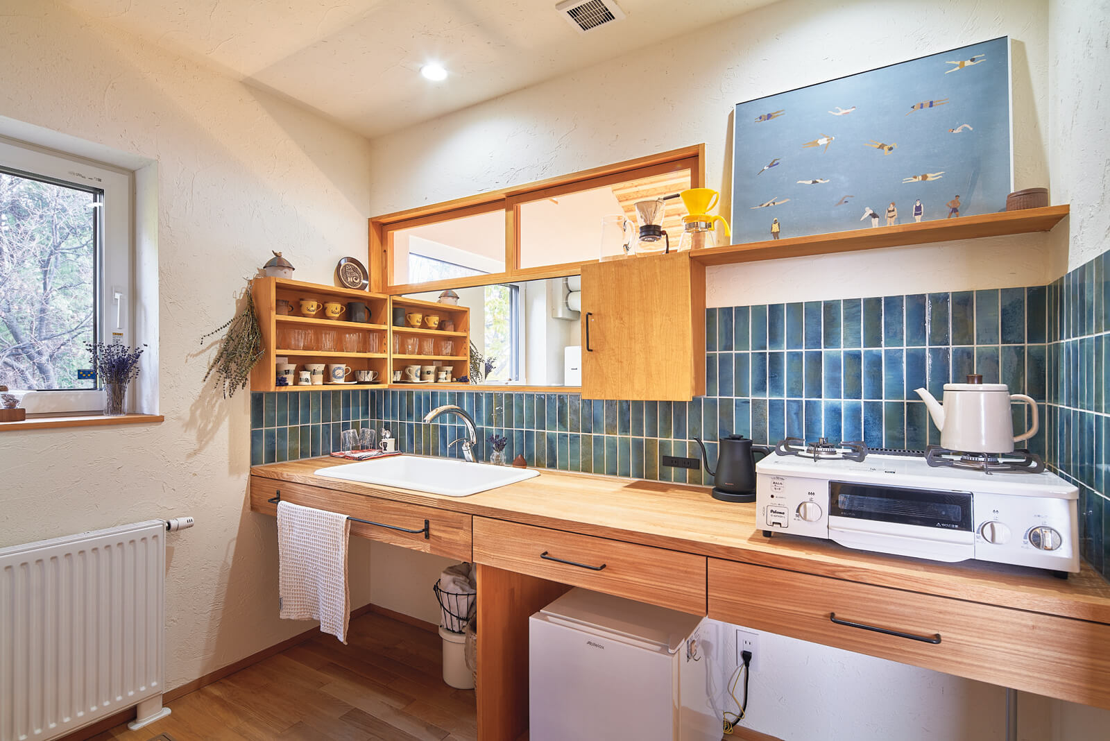 浴室のあるランドリールームに洗面所兼用の簡易キッチンを造作。メインキッチンと同じブルーのタイルが映える