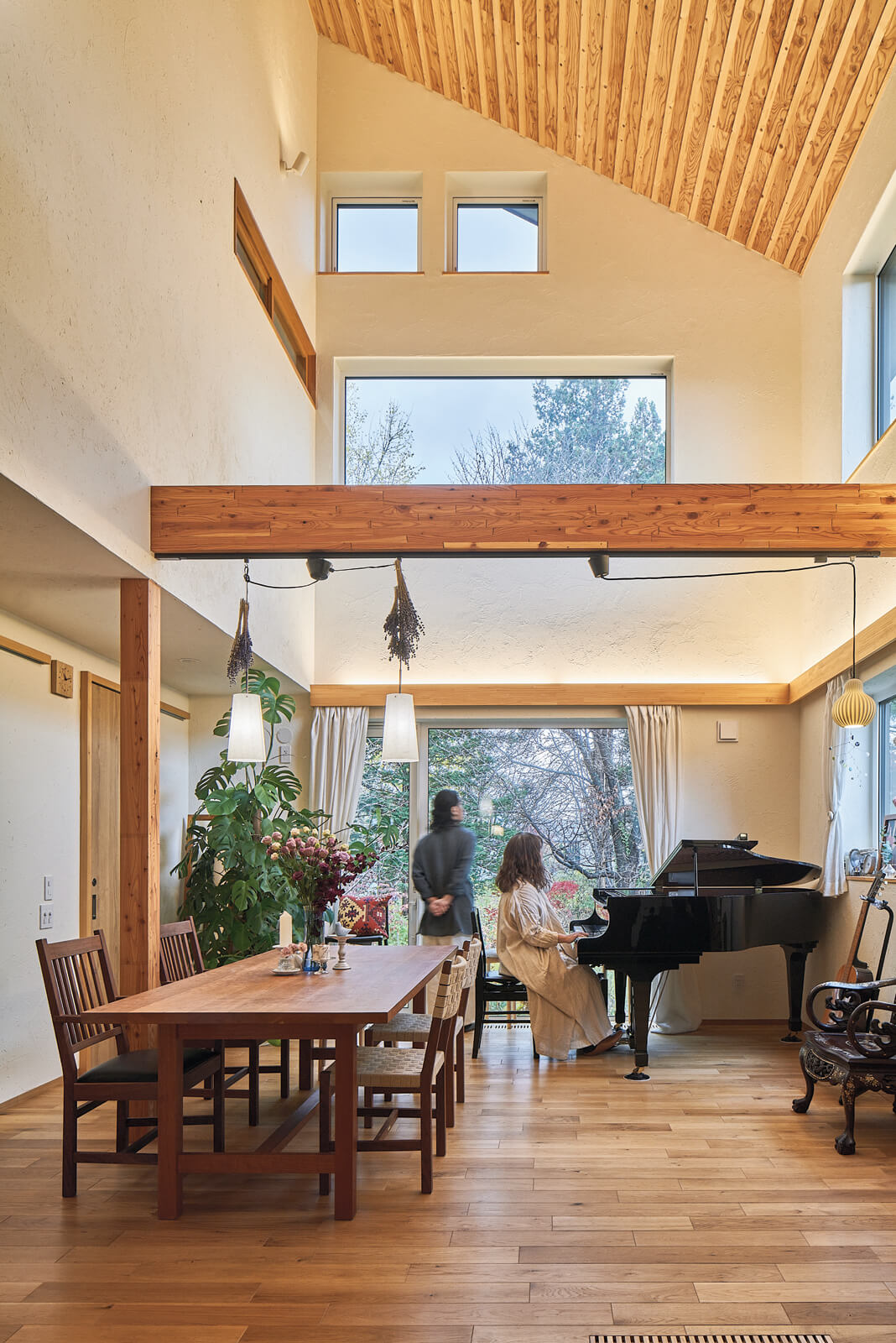 グランドピアノを置いても開放的な吹き抜けのリビング・ダイニング。普段は歌やギター、ピアノのレッスンに使用。壁面はすべて藁を塗り込んだ珪藻土で音の響きもよく、時にはここでコンサートも。庭にある大きなサクラが美しく見えるよう、家の向きや窓の大きさ、配置にもこだわった