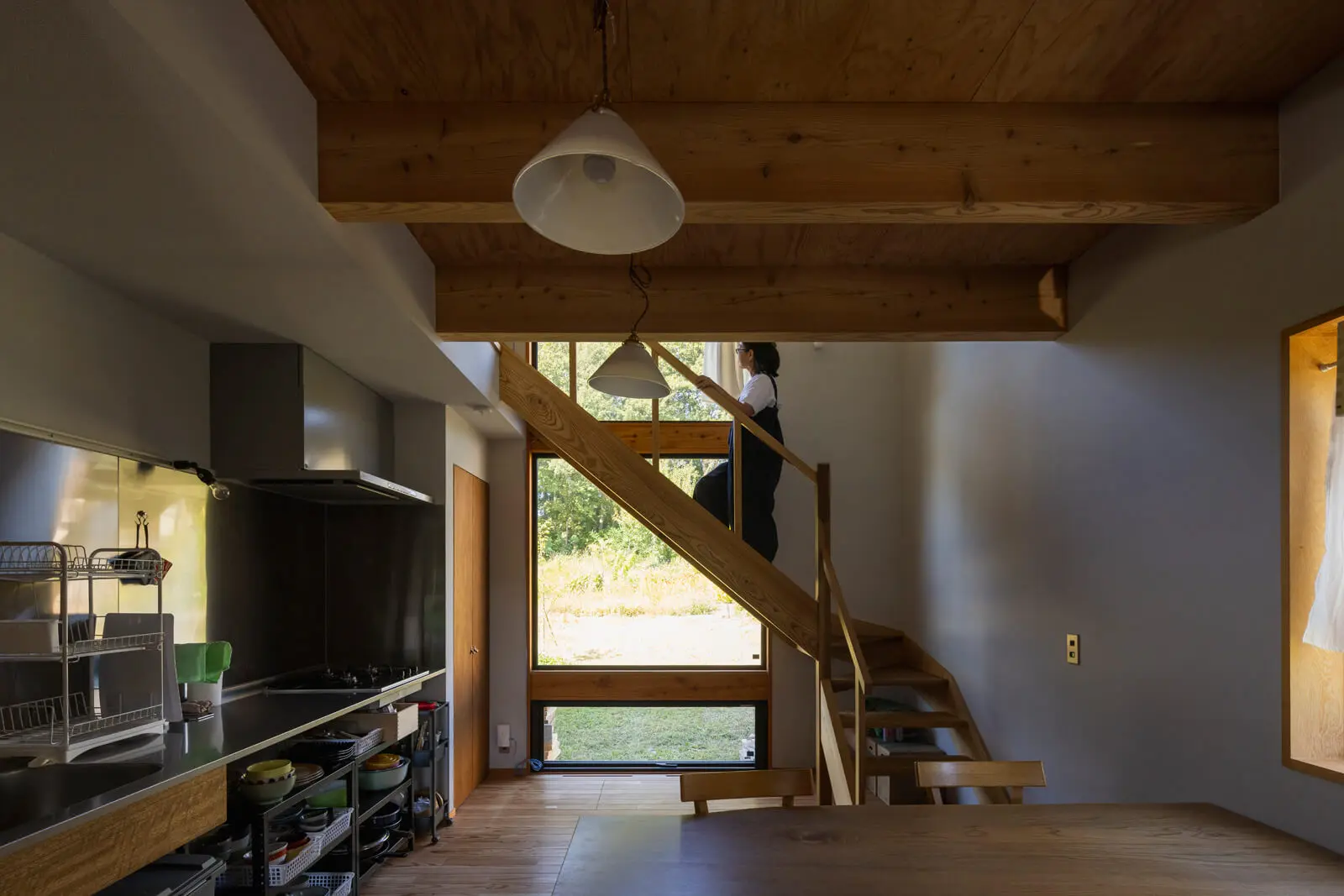 現しの梁にガイシ配線を採用したダイニングキッチン。住まい手の使い勝手に柔軟に寄り添えるよう、キッチンの設備も最小限に留めた