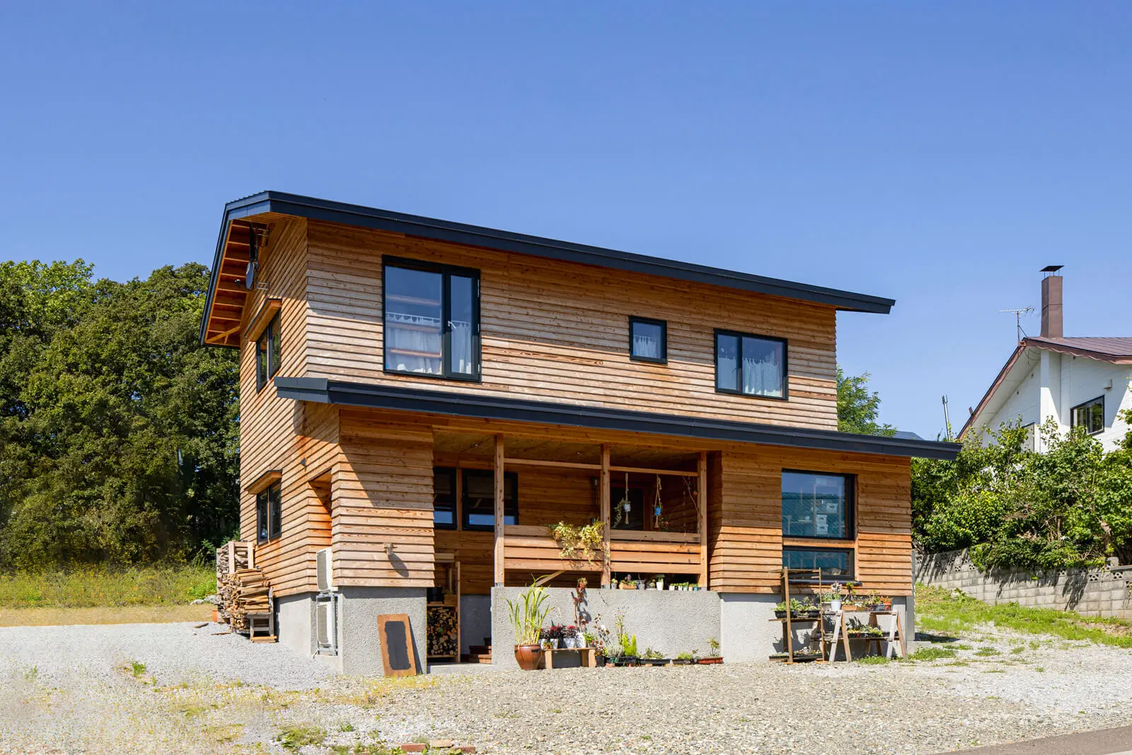 傾斜地の土地なりに設えた建物は、緩やかな坂道を上り、見えた景色にすっきり納まる配置にこだわった。外壁は経年変化が楽しめるカラマツ荒木材の下見板張り