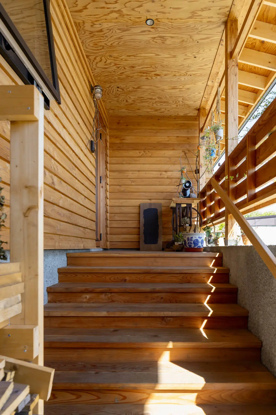 カラマツの温かな木目に包まれるような玄関ポーチ。手すりや階段、軒天など細かな収まりにも気を配った