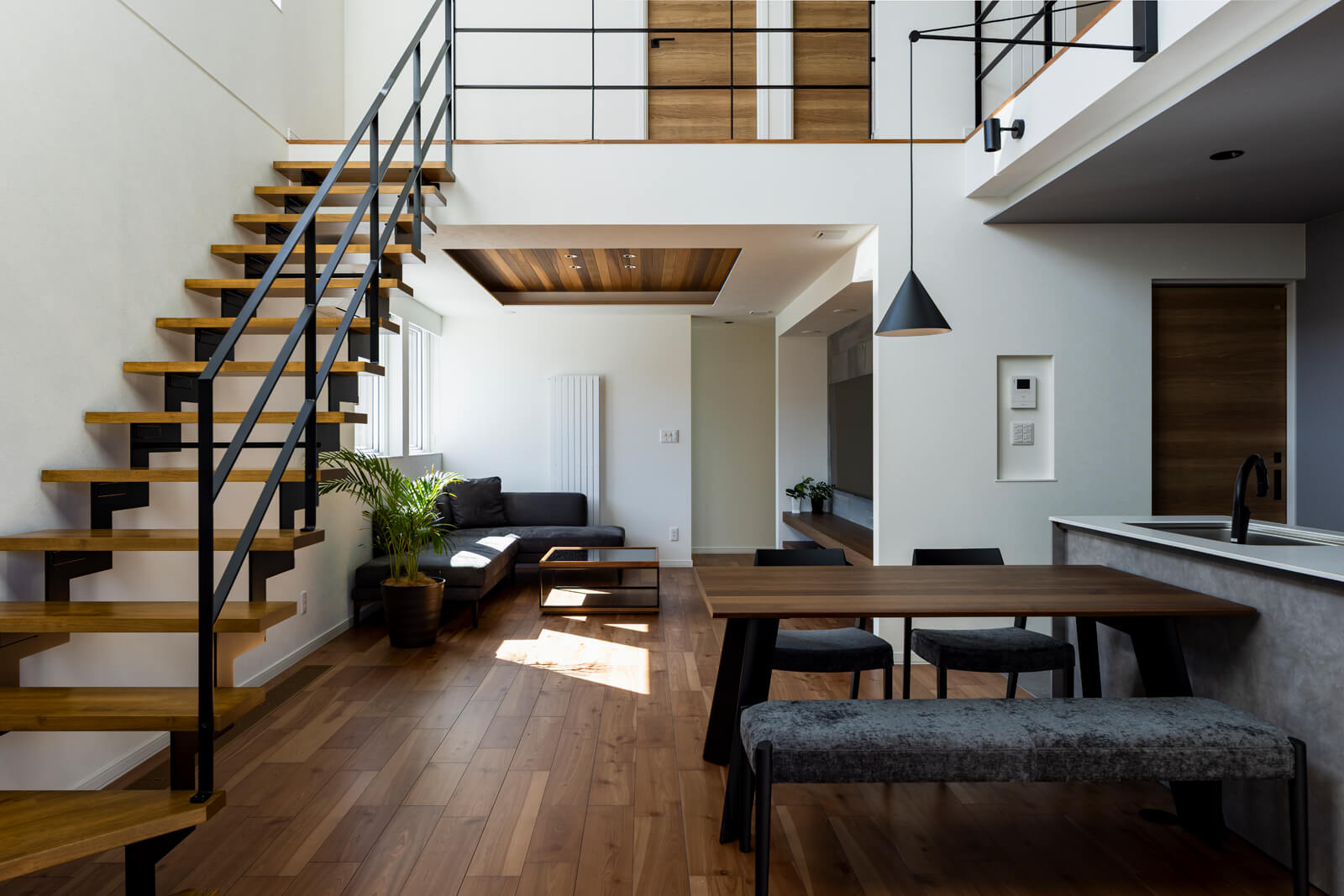 ダイニングからリビングを見る。天井高の変化で空間を緩やかにゾーニング。見上げた目線の先には、子ども部屋の扉がある