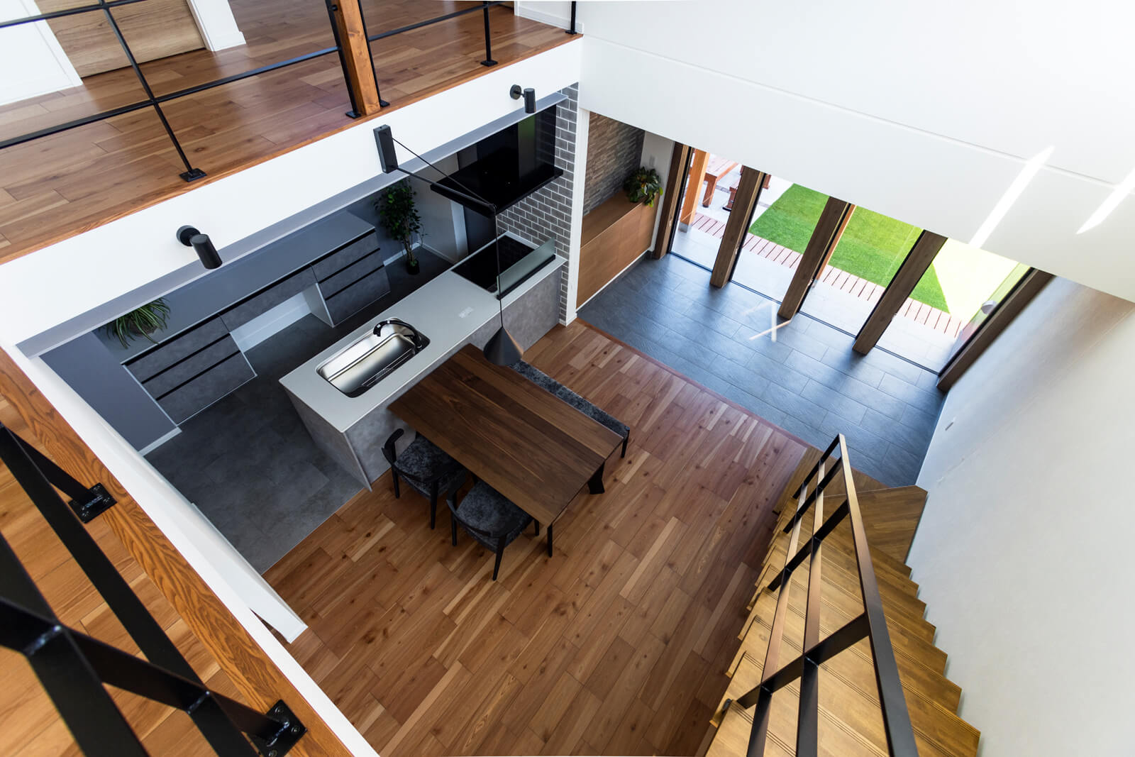 吹き抜けからの見下ろし。土間越しの裏庭まで視線が抜け、心地よい開放感に包まれる