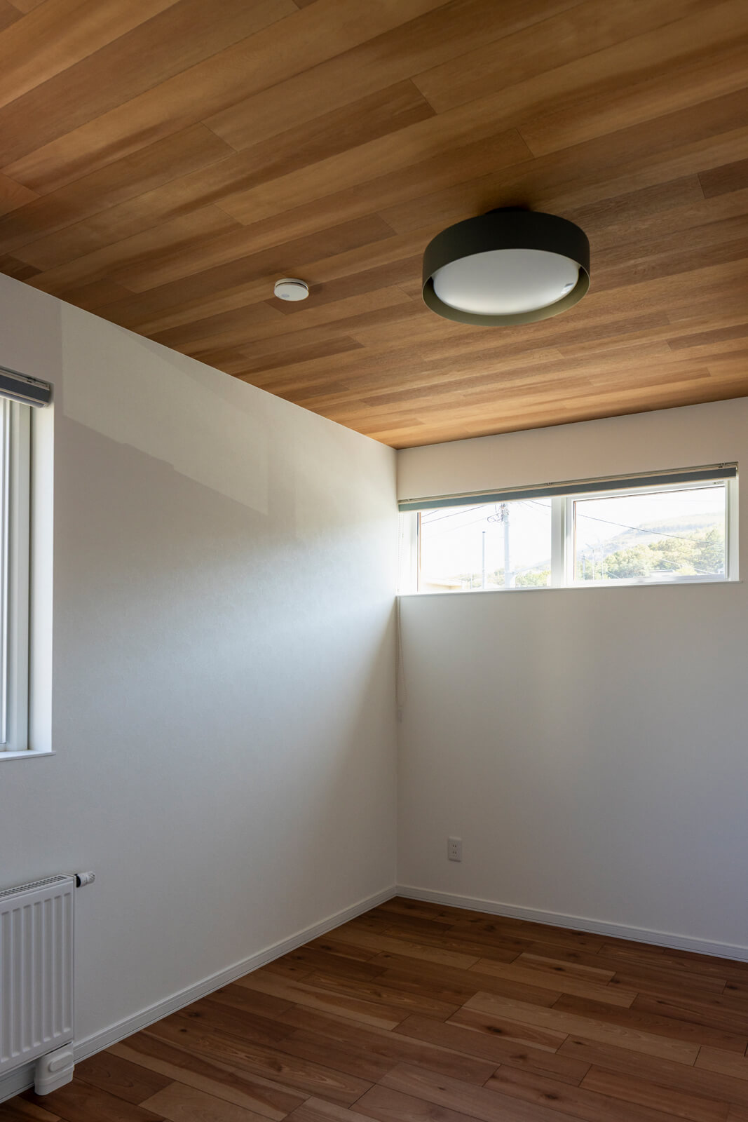 天井に木目調クロスを張り、統一感を演出した2階寝室。入り口側には、容量たっぷりのウォークインクローゼットも設置