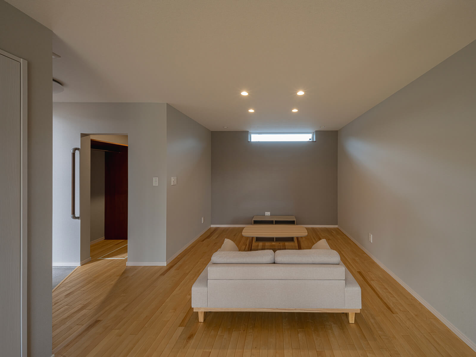 グレーの壁紙でやわらかくアクセントをつけたリビングの床にはカバの無垢フローリングを採用