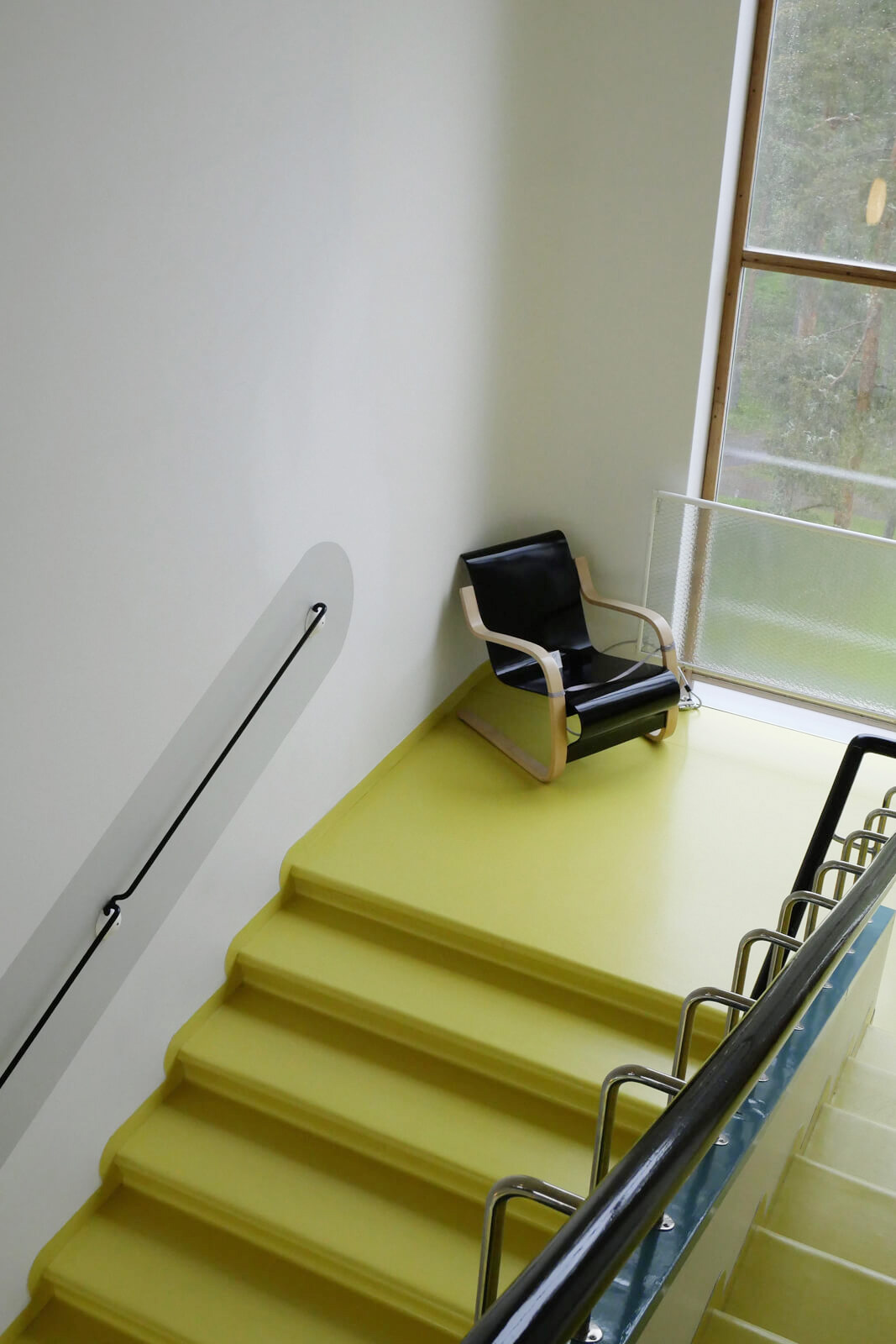 現代まで愛されている名作「パイミオチェア」が置かれた階段は、鮮やかな「パイミオイエロー」