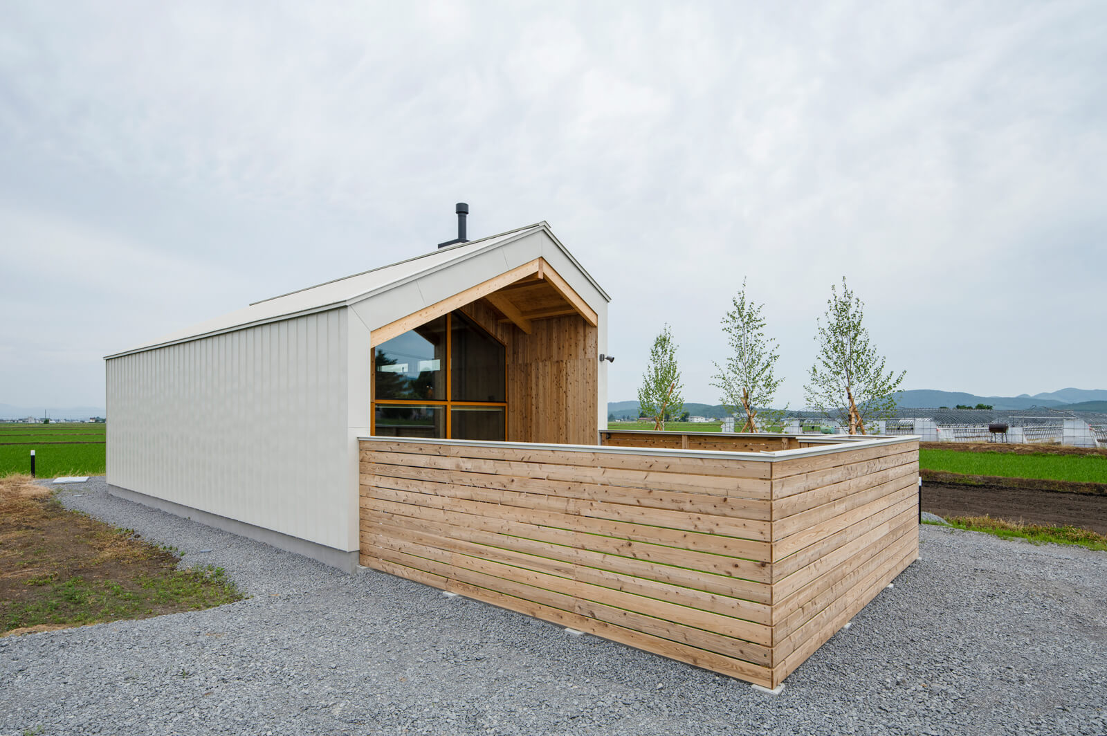 太田さん兄弟が運営する一棟貸しのコテージ。白いガルバリウム鋼板の外壁は洗練された印象を与えつつ、東川町の自然になじんでいる。ウッドフェンスで囲まれているのはドッグランで、バーベキューを楽しむこともできる