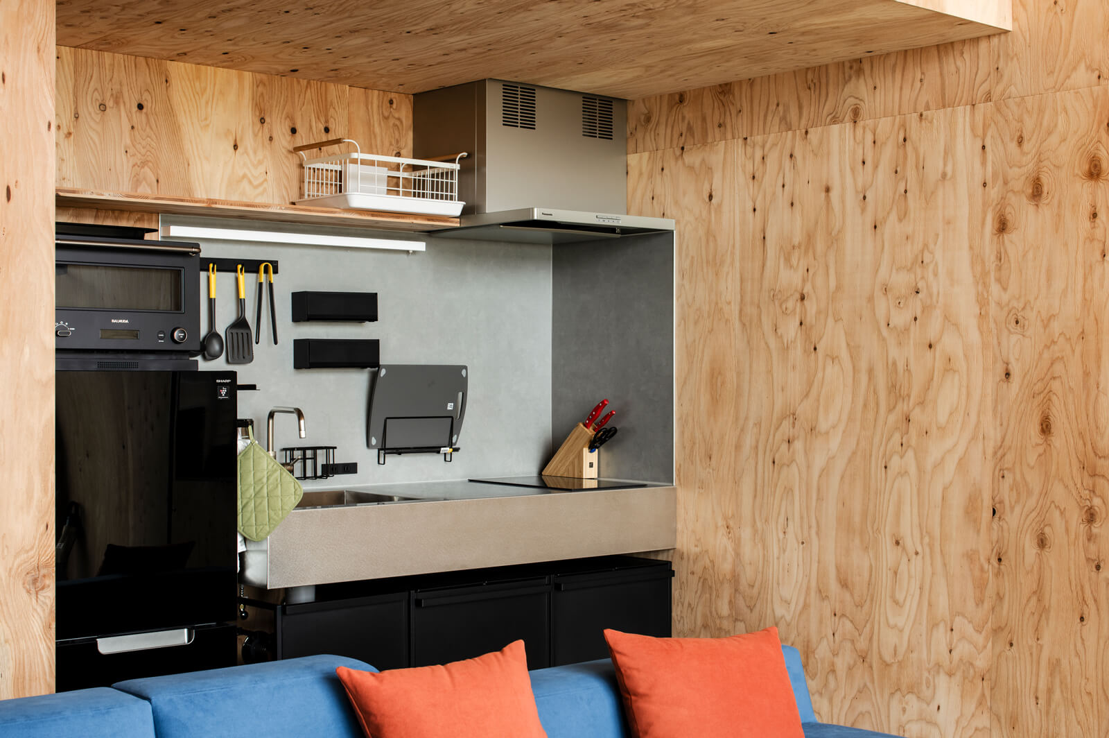 コンパクトサイズの壁付けキッチン。壁面のマグネット機能を用いたキッチンツールの収納アイデアは、住宅でも生かせそう