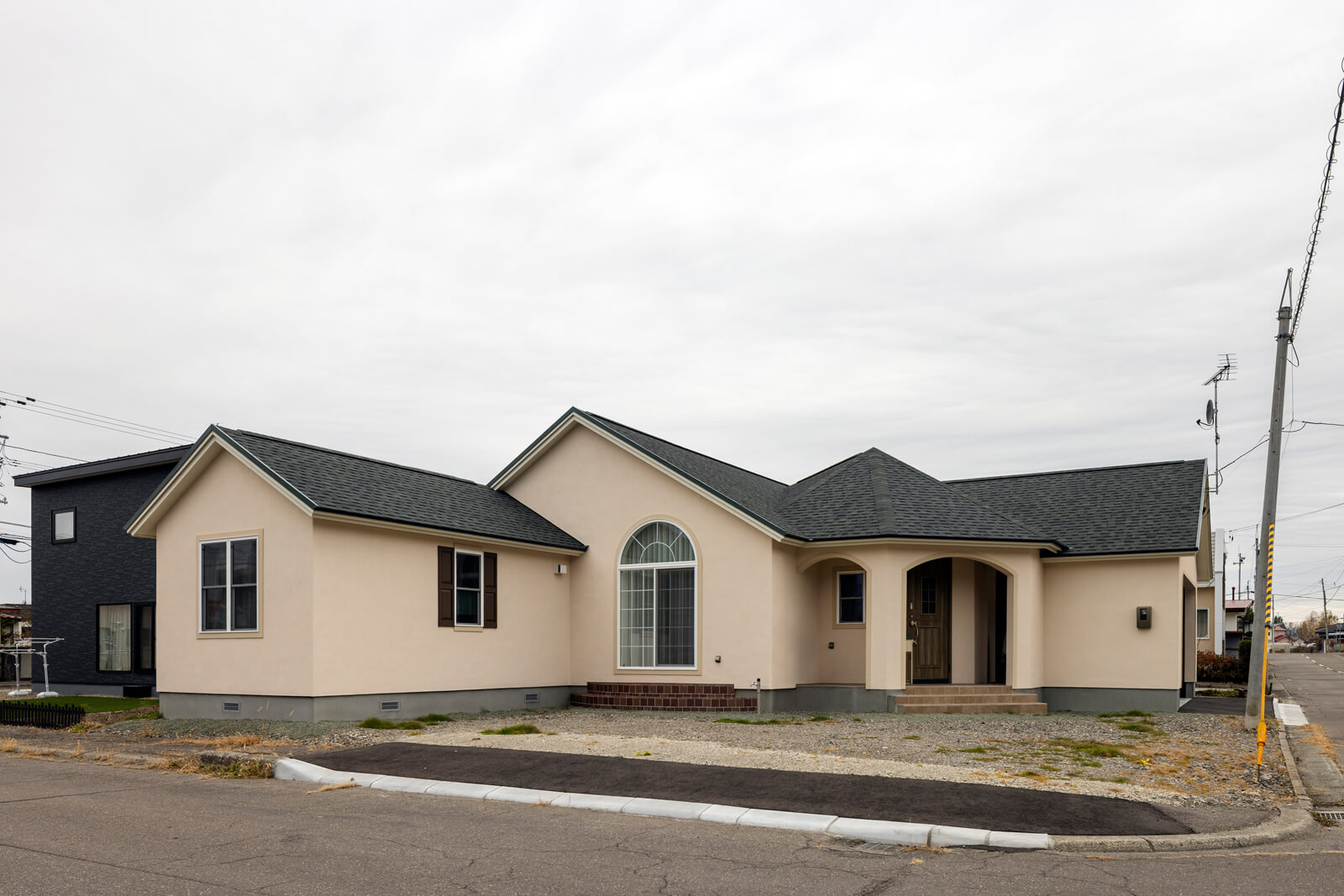 角地の敷地形状を生かしたL型のフォルムに、三角屋根と寄棟屋根を組み合わせ、塗り壁で仕上げた外観。個性的な佇まいが、地域でも話題に